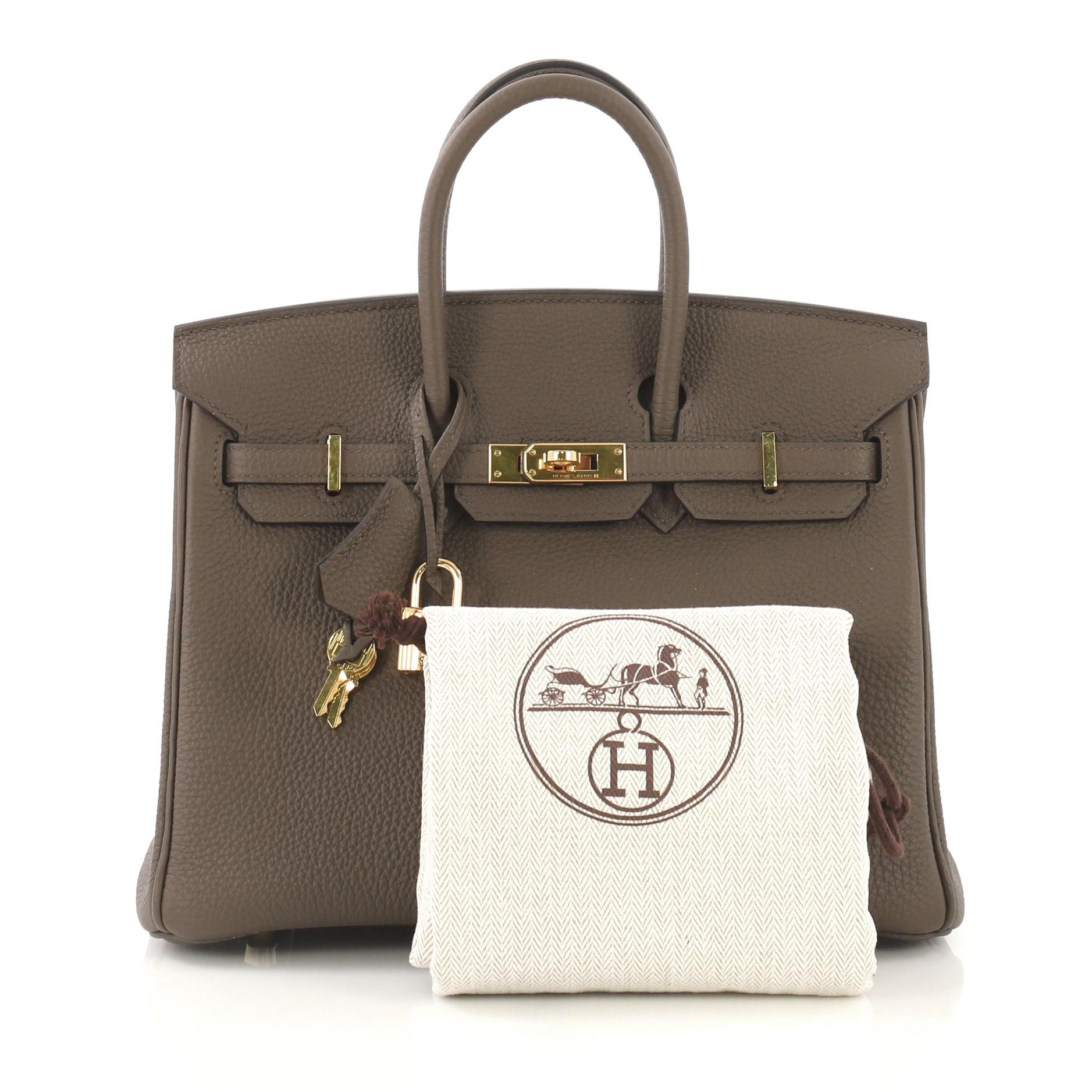 This Hermes Birkin Handbag Taupe Togo with Gold Hardware 25, crafted in Taupe Togo leather, features dual rolled handles, frontal flap, and gold hardware. Its turn-lock closure opens to a Taupe Chevre leather interior with a slip pocket. Date stamp