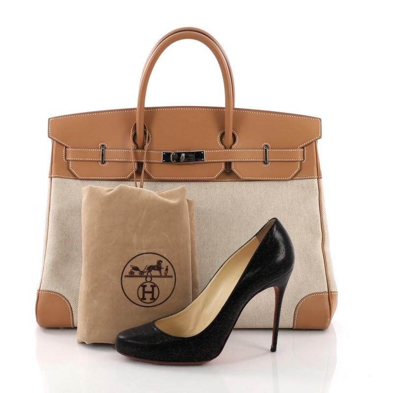 This Hermes Birkin Handbag Toile and Brown Chamonix with Palladium Hardware 40, crafted from natural and ecru toile and leather, features dual rolled top handles, frontal flap, protective base studs, and palladium-tone hardware. Its turn-lock