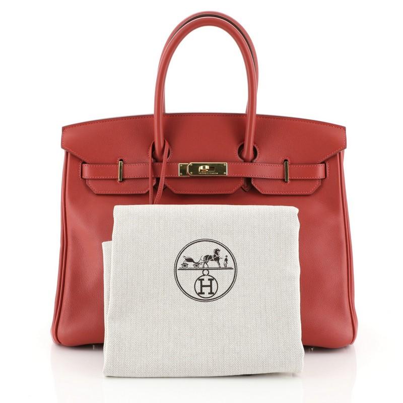 This Hermes Birkin Handbag Vermillion Swift with Gold Hardware 35, crafted in Vermillion red Swift leather, features dual rolled top handles, frontal flap, and gold hardware. Its turn-lock closure opens to a Vermillion red Swift leather interior
