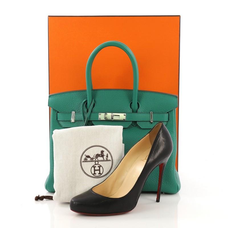 This Hermes Birkin Handbag Verso Clemence with Palladium Hardware 30, crafted in Vert Vertigo green Clemence leather, features dual rolled top handles, frontal flap, and palladium hardware. Its turn-lock closure opens to a Vert Fonce green Chevre