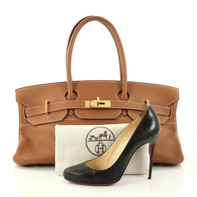 This authentic Hermes Birkin JPG Handbag Brown Clemence with Gold Hardware 42 aptly named from its designer Jean Paul Gaultier is an elongated reinterpretation of the Hermes' classic Birkin design. Crafted from gold brown clemence leather, this