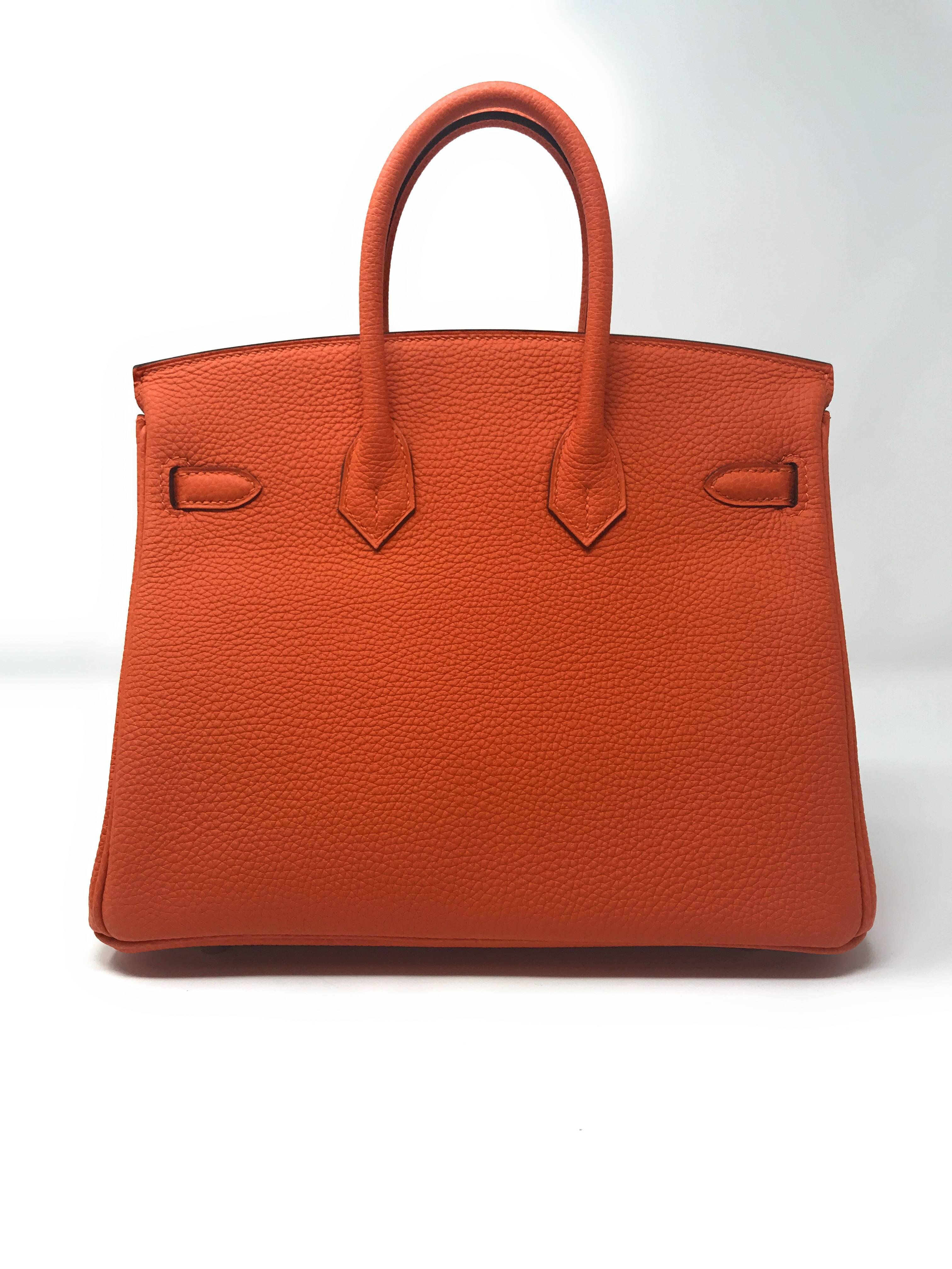 This rare Hermes Birkin bag is the “must have” accessory for any wardrobe. It’s the “Mini” 25cm size crafted in scratch resistant 
Togo leather in Hermes Orange Feu, meaning fire. 
The signature Hermes color is quite eye catching and because of it’s
