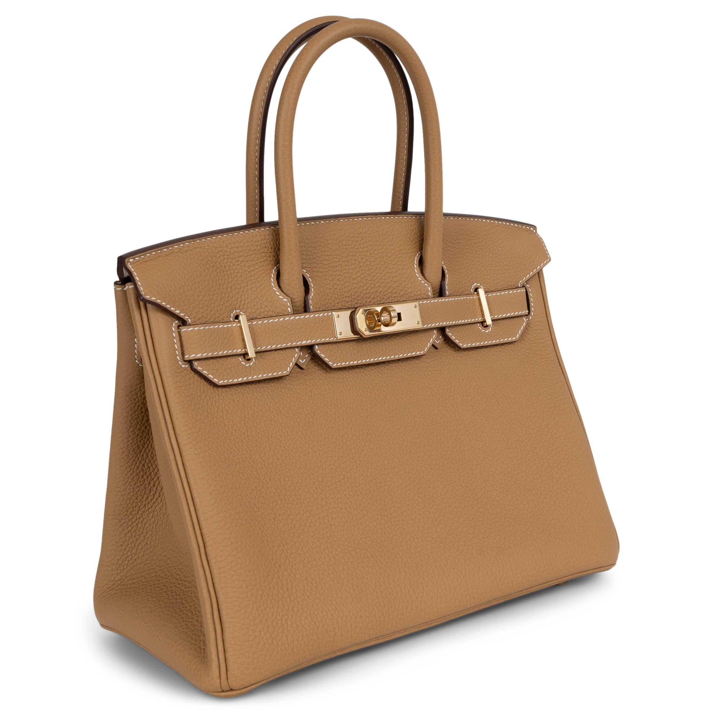This 100% authentic Hermès Horseshoe Birkin 30 is crafted from Biscuit (beige) Veau Togo leather with contrasting white stitching and an exclusive custom lining in Nata Chèvre (goat skin)—a bespoke touch reserved for special orders. Finished with