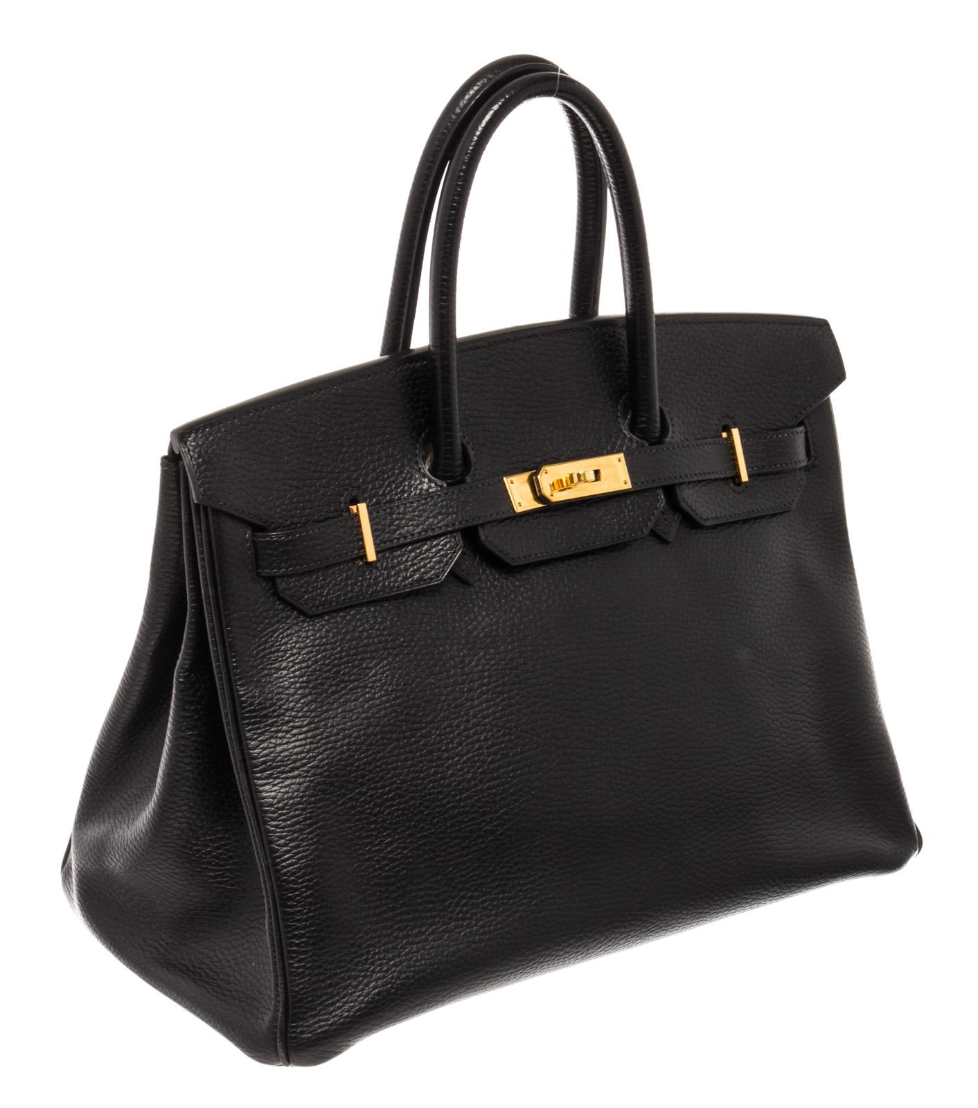 This classic Hermes Birkin 35 cm handbag is done in black Ardennes leather. It features gold-tone hardware, dual rolled top handles and a black Chevre leather-lined interior. The interior has one large compartment, one slide pocket, and one zip
