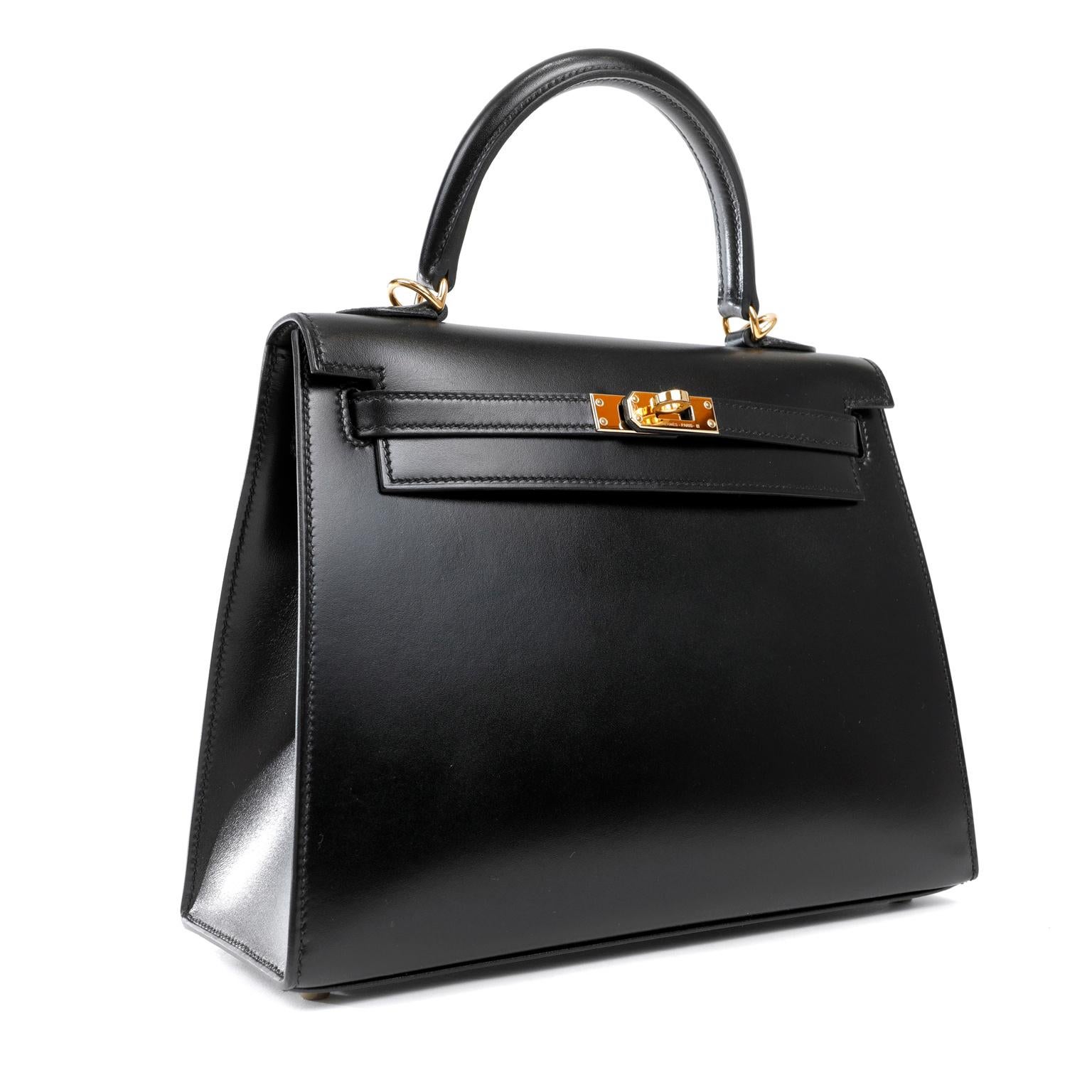 This authentic Hermès Black Box Calf 25 cm Kelly is in totally pristine condition. Hermès bags are considered the ultimate luxury item worldwide. Each piece is handcrafted with waitlists that often exceed a year. The ladylike Kelly is classic and