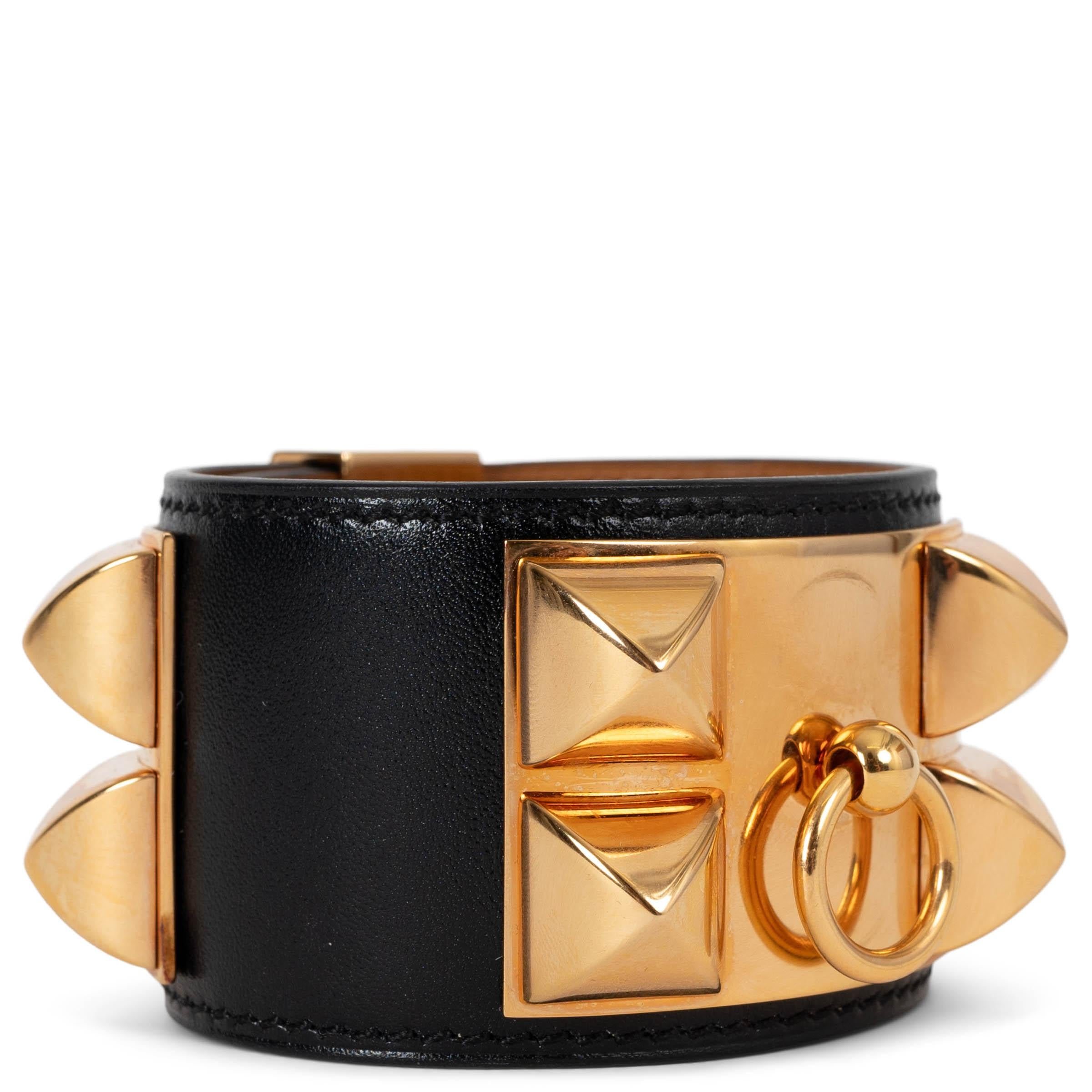 This 100% authentic Hermès Collier de Chien cuff bracelet in black Box leather is a bold statement piece, celebrated for its structured design and luxurious craftsmanship. Accented with rose gold-plated hardware, it features the signature Médor