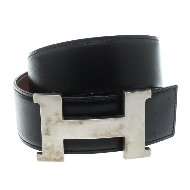 A classic add-on to your collection of belts, this Hermes piece has been crafted from leather. It is reversible with a black shade on one side and brown on the other. It is topped with an H buckle in silver-tone. This wardrobe essential piece will