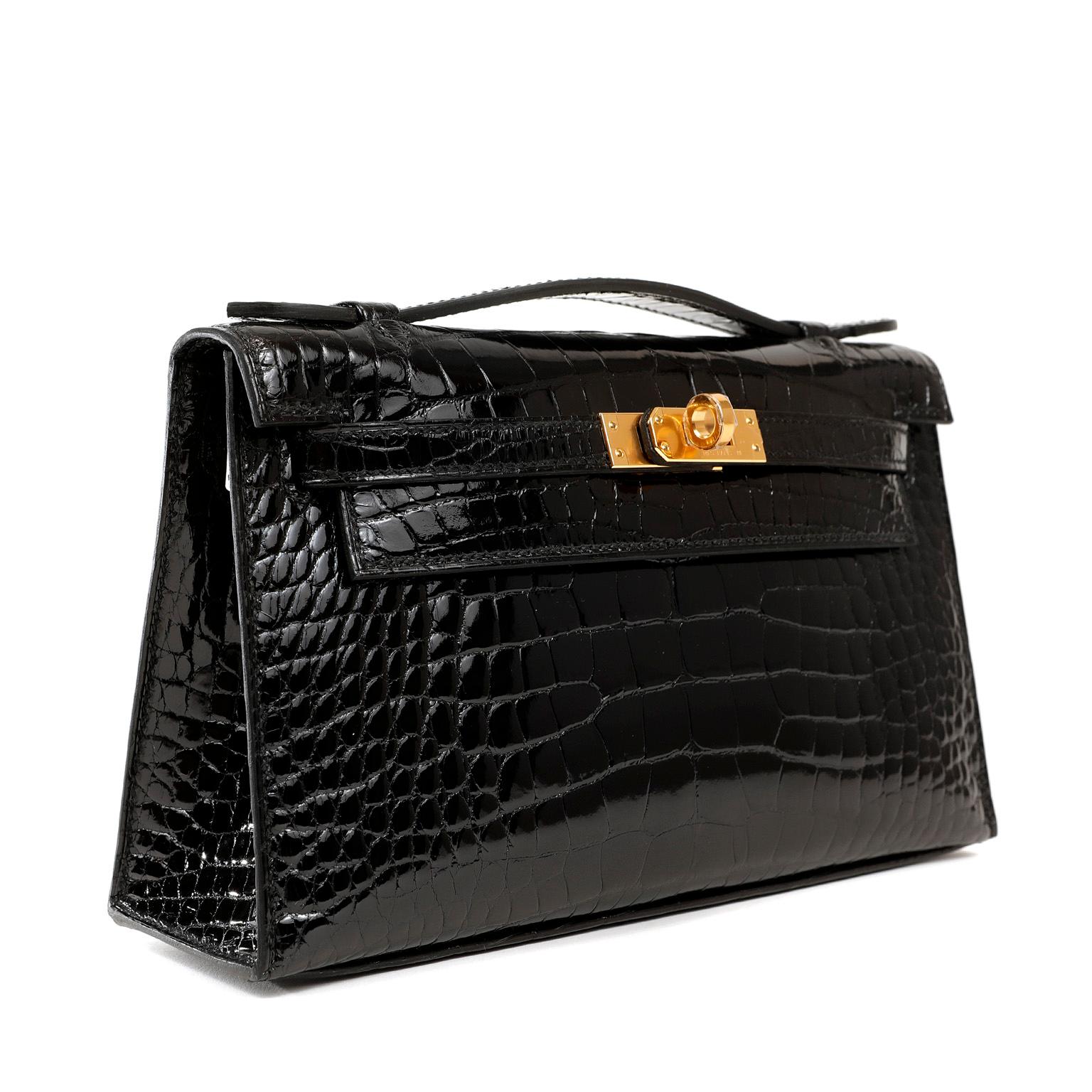 This authentic Hermès Black Crocodile Kelly Pochette is in pristine unworn condition with the protective plastic on the gold hardware. A clutch version of the classic Kelly, it has a stable base allowing it to stand upright and easily carries all