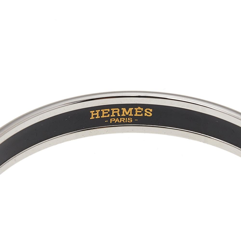 A style element to flaunt with pride is this one by Hermès. It is sculpted from palladium-plated metal and designed with gorgeous enamel work. The bangle bracelet has the brand's stamp on the inner side of the band.

Includes:, Original Box,