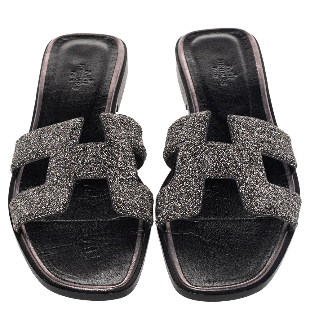 Add the iconic Hermès Oran sandals to your shoe collection with this pair. These black Oran sandals have been crafted in Italy and they feature the iconic H detailed with glitter and leather-lined insoles to provide comfort at every step.

Includes:
