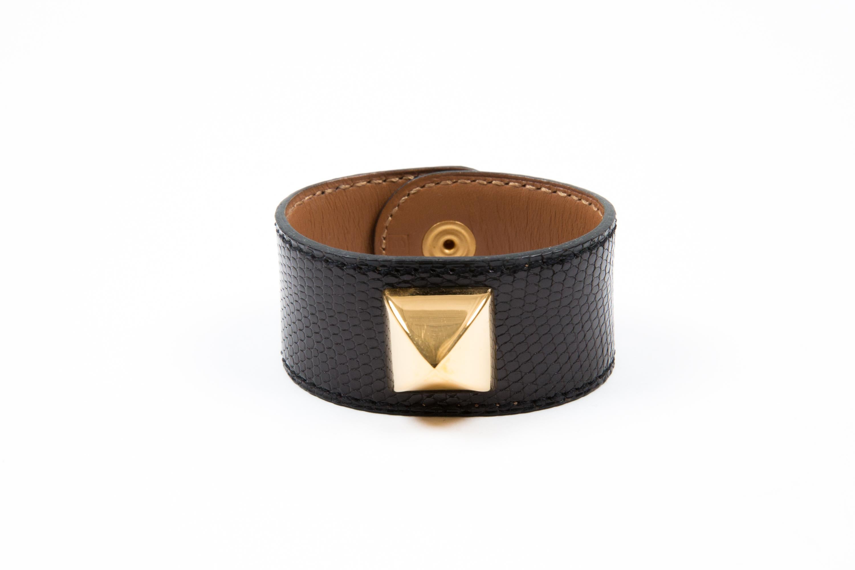 Hermès Black textured leather stud “Medor” bracelet featuring a gold-plated stud, a logo gold-tone snap, an inside camel leather, an inside logo stamp, a B in a square. 
Circa 1998 
Size: Small 
Made in France, pitted Hermès 
Circa 1998
Length: