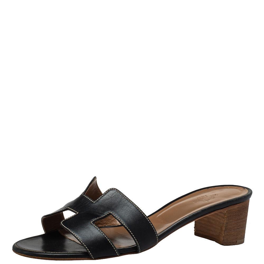 A seamless blend of luxury, comfort, and class is what you get when you slide your feet into these Hermès sandals. Crafted from black leather, they feature the signature H-shaped straps on the front and are set on comfortable block heels. These