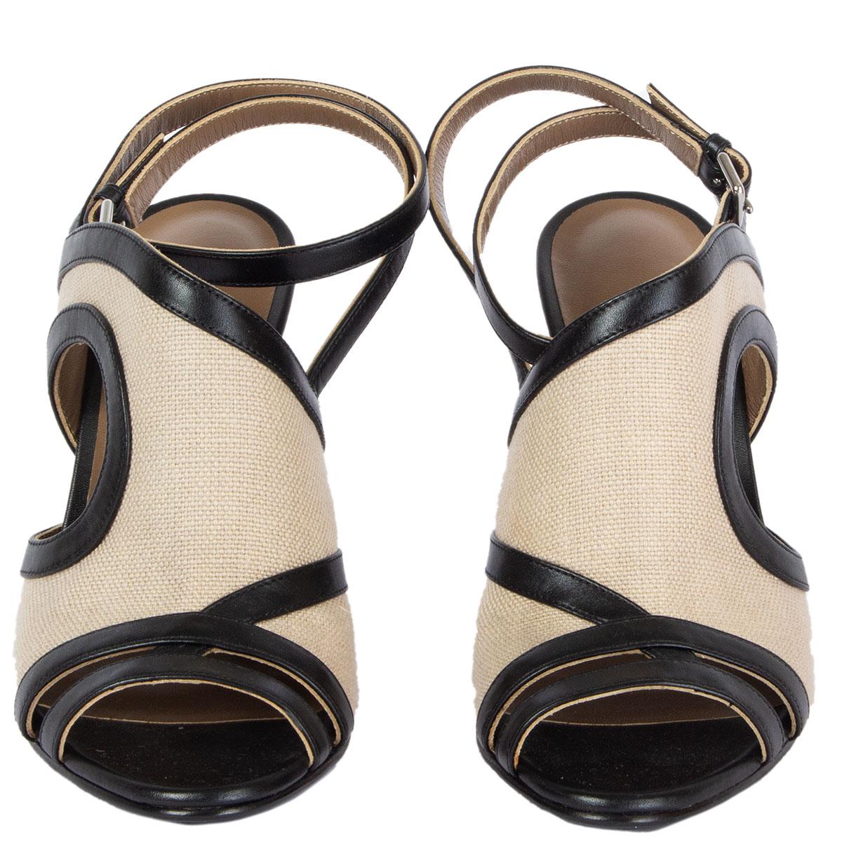 100% authentiques sandales Hermes Rafaella en toile taupe avec talon et garniture en cuir noir. État neuf. Livré avec un sac à poussière. 

Mesures
Taille imprimée	38
Taille des chaussures	38
Semelle intérieure	24.5cm (9.6in)
Largeur	7.5cm
