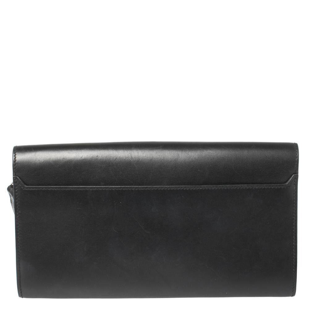 This Goodlock clutch from Hermes is a statement piece you must own! It has been crafted from black leather and adorned with a logo-engraved palladium hardware lock on the front flap. It opens to a leather interior that can easily accommodate your