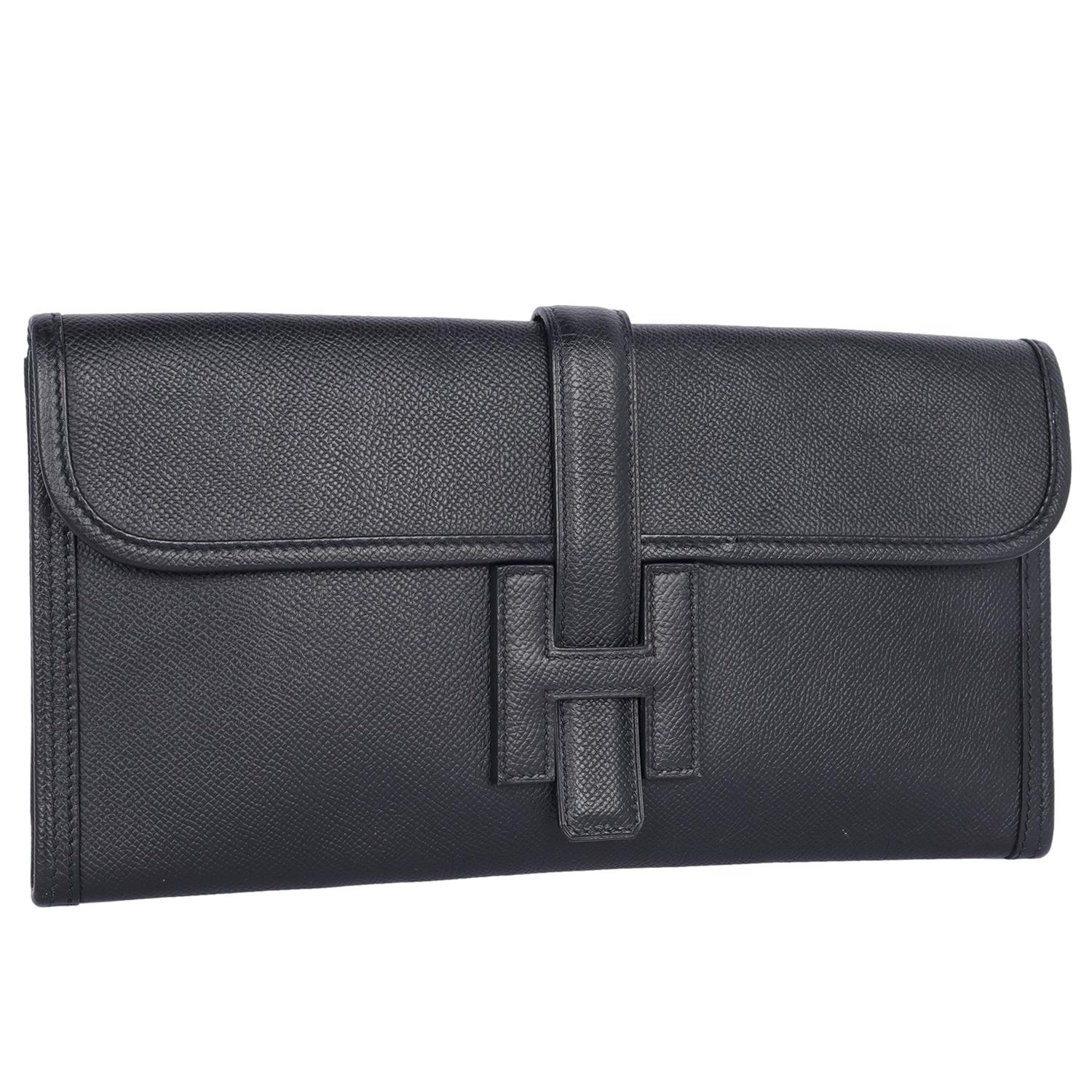 Authentic, pre-loved Hermes Swift Jige Elan 29 Clutch in black.

The clutch bag features swift calfskin leather in black. The bag has a front flap closure with a strap that tucks under the leather Hermes 