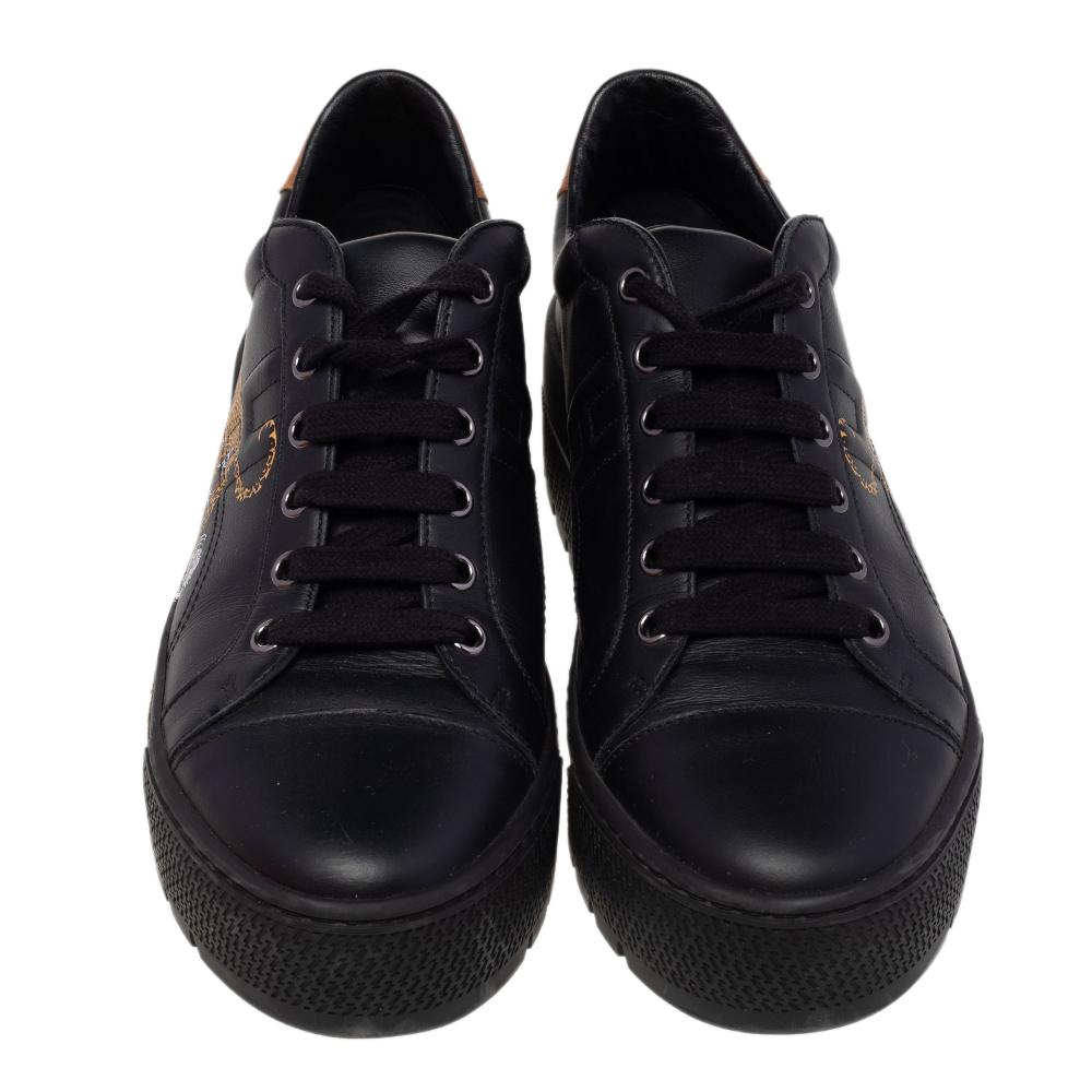 The sneakers by Hermes present a classic style in a modern tone. These are crafted in black leather and detailed with an interesting jungle print on the sides and a logo-accented contrasting panel on the counters. The sneakers are secured with