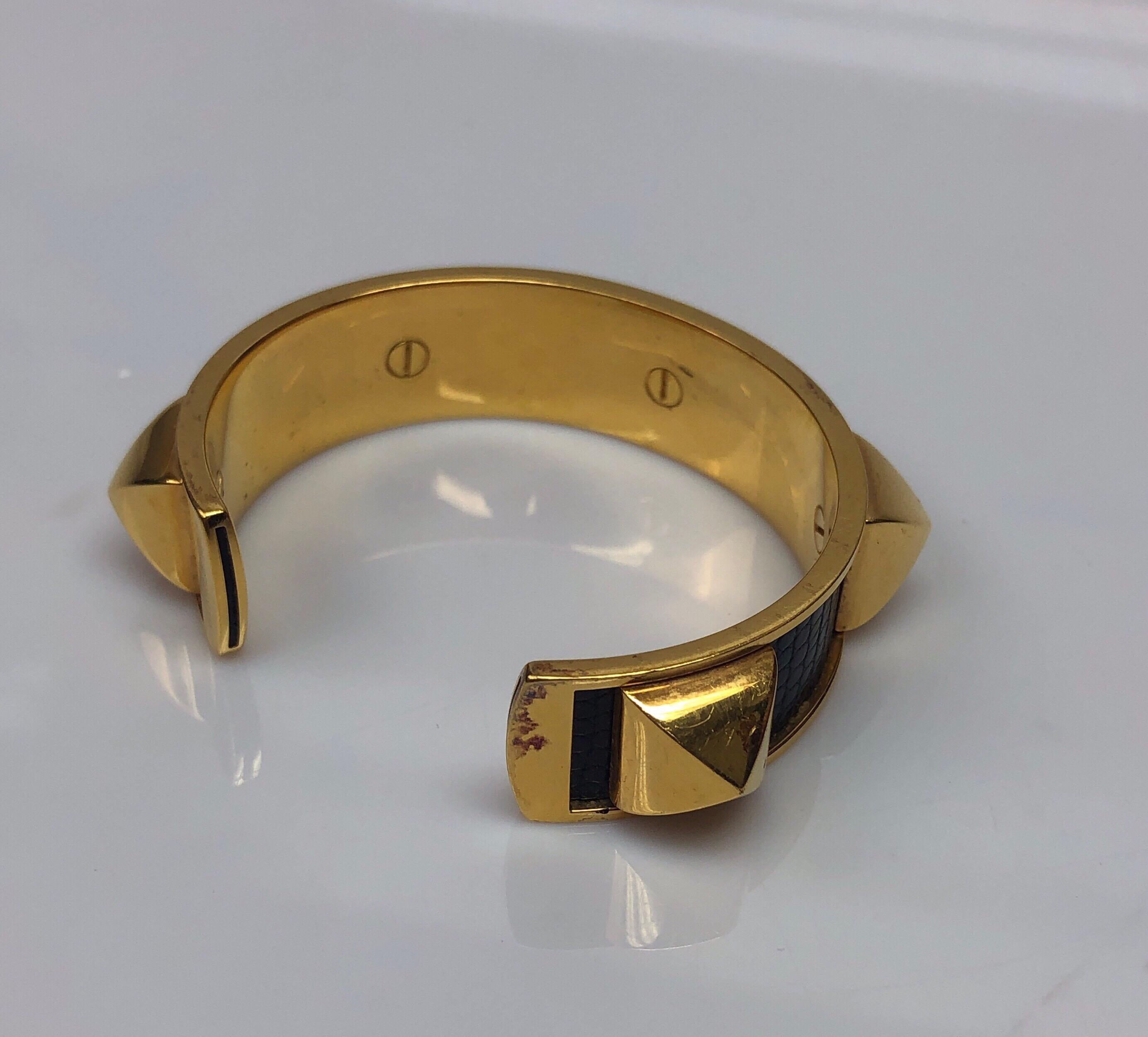 Hermès Black Lizard Matador Studded Gold Cuff. This beautiful cuff bracelet is in good condition. There are minor scrapes and markings on the metal (shown in picture). It has black lizard all throughout with large gold studs attached. This cuff is a