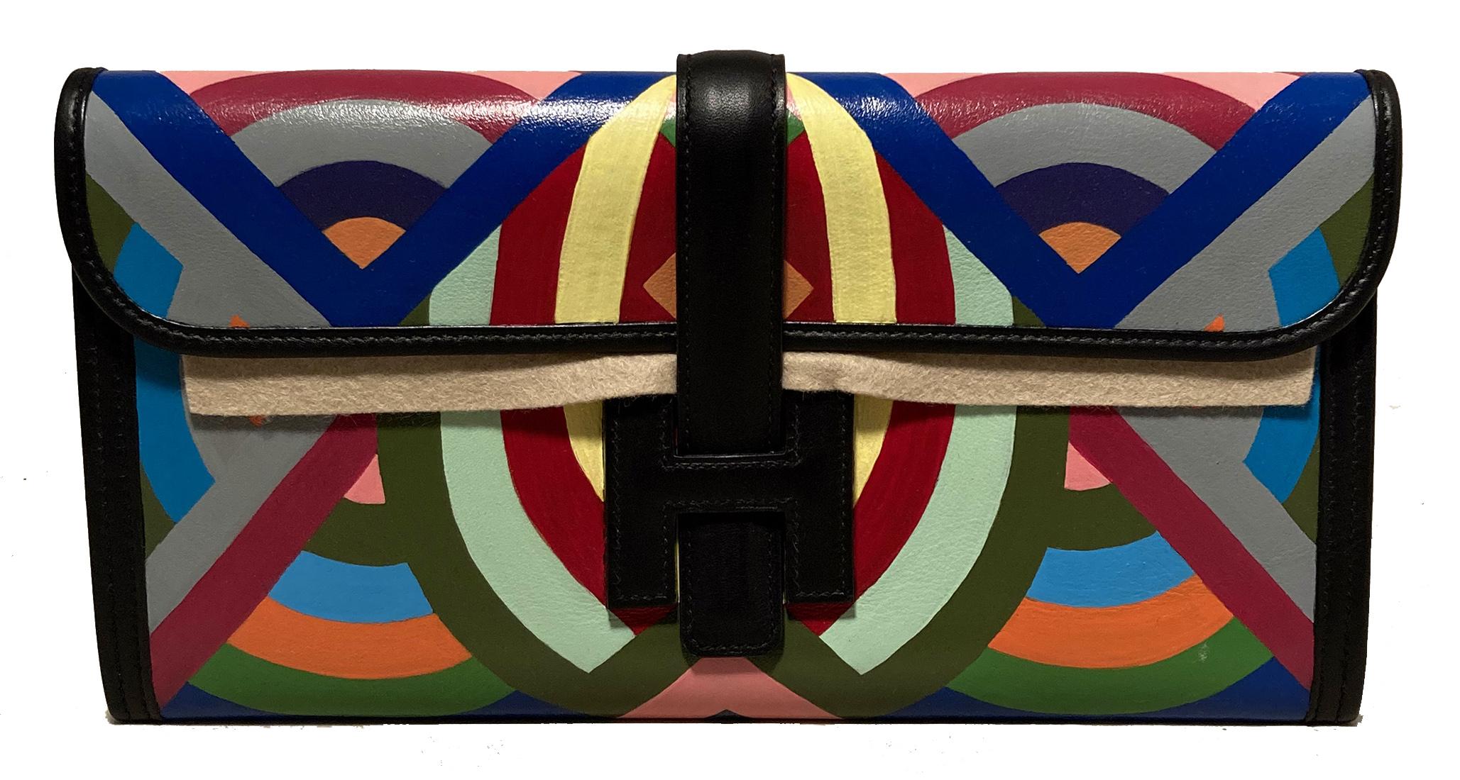Hermes Black Painted Jige 28 Clutch in excellent condition. Black swift leather with colorful geometric hand painted design featuring grey, blues, greens, reds, pink, yellow and orange surrounding exterior. Front H leather strap closure opens to a