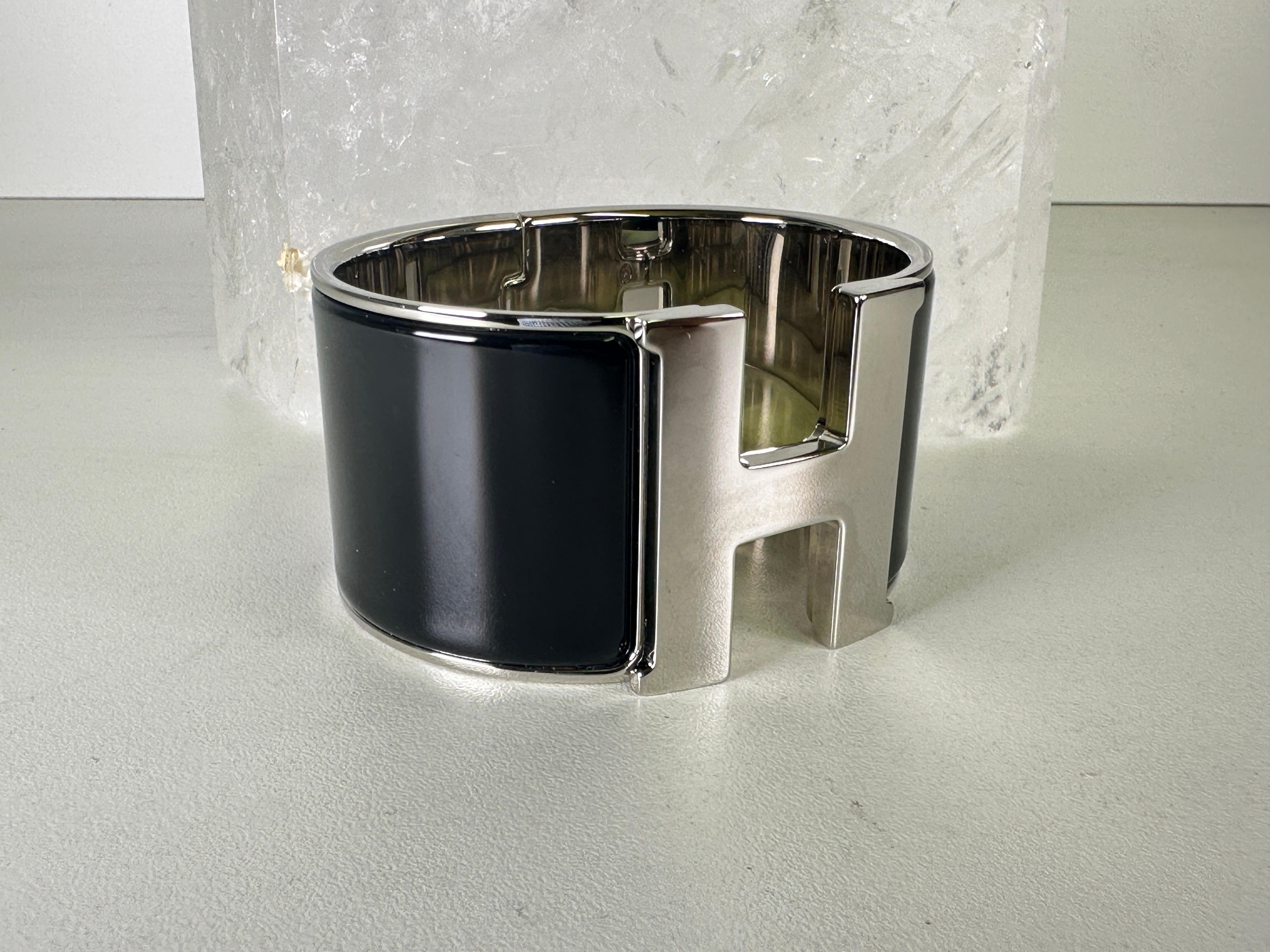 Bracelet Clic Clac extra-large en émail noir / palladium d'Hermès. Légèrement usé, encore sous film plastique protecteur. Livré avec une pochette et une boîte.
Acheté à Hermes on Rodeo Dr.