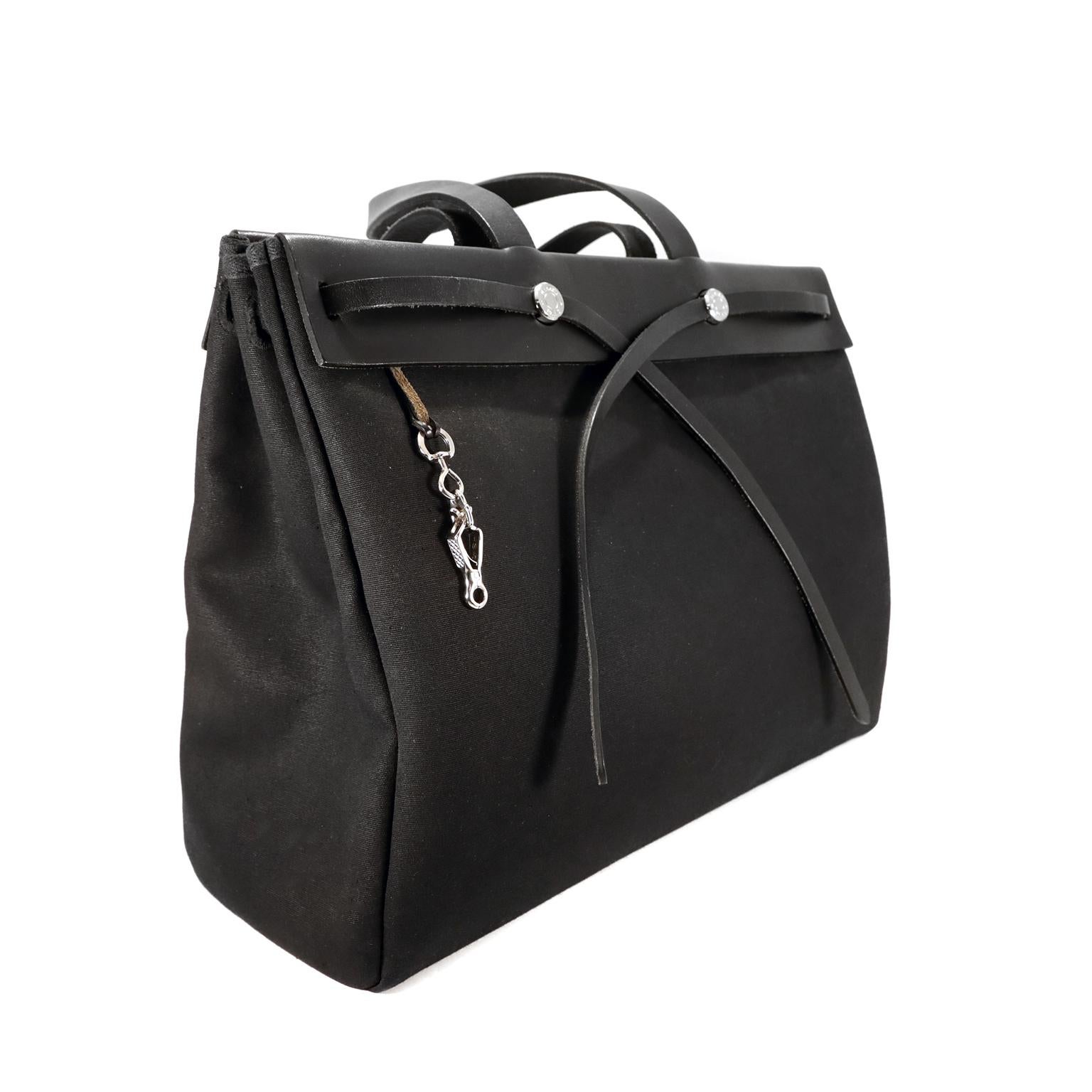 This authentic Hermès Black 40 cm Herbag Cabas Tote is in excellent condition.  Black toile canvas body with sleek black calfskin accents and straps. Also known as the 2 in 1 bag for the smaller interior canvas bag that can be substituted for the