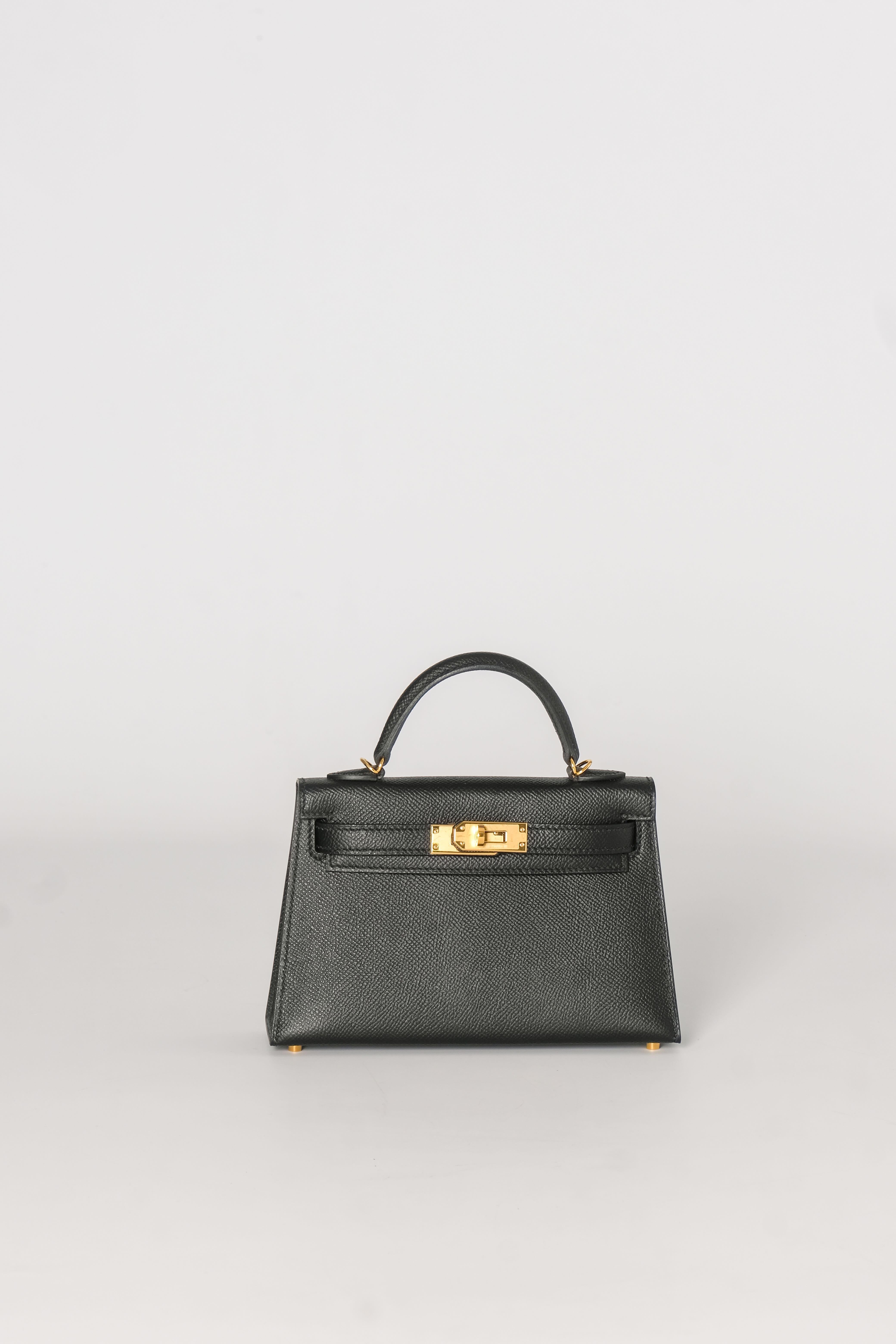 This handbag is crafted in stamped Epsom calfskin leather in classic black. A single rolled leather top handle is secured with gold-plated hardware and an optional leather shoulder strap is included. The traditional Kelly turn-lock secures the small