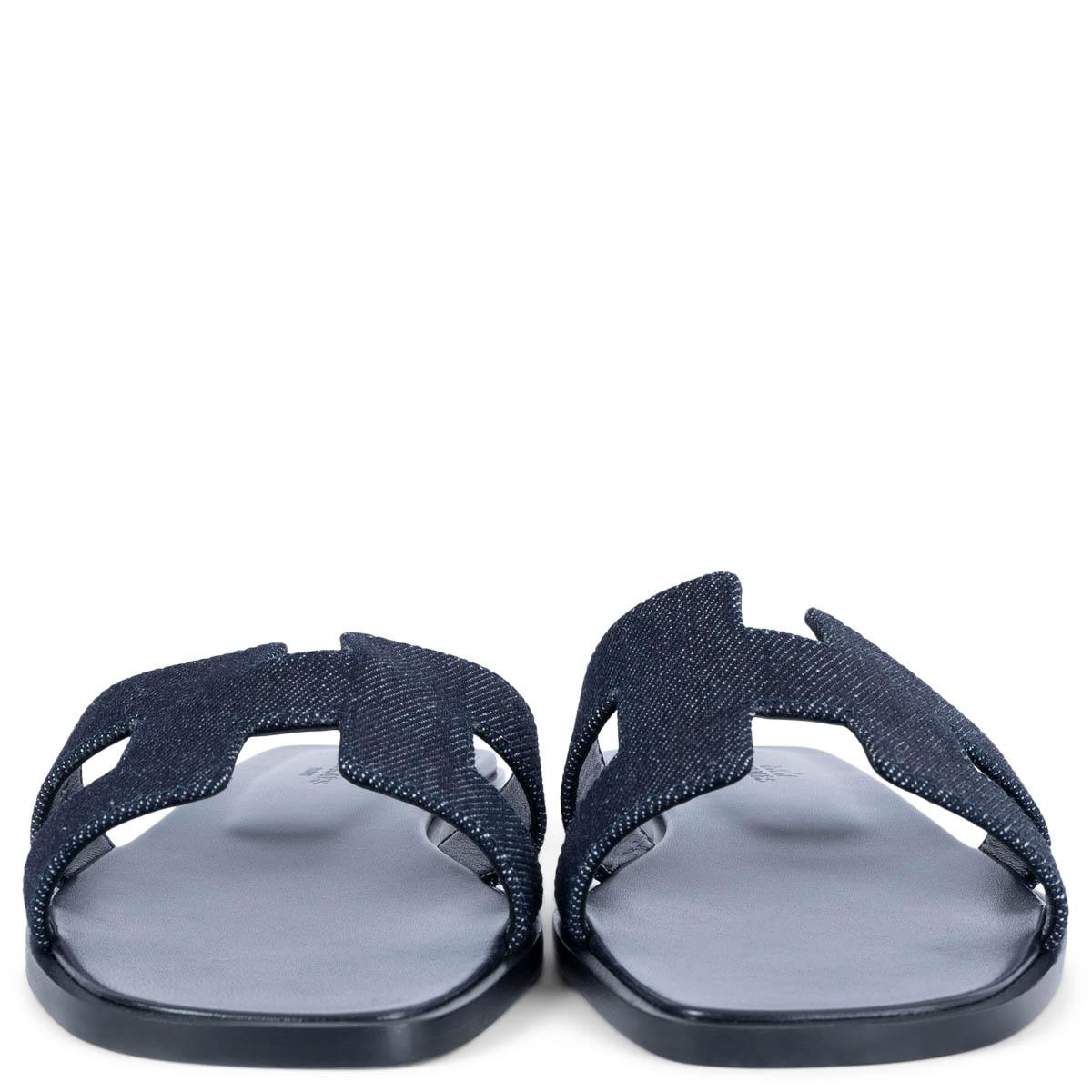 100% authentic Hermès Oran sandals in Bleu Brut (dark blue) denim with iconic H cut-out. Brand new. Come with dust bags. 

Measurements
Model	H021056Z 01340
Imprinted Size	37.5
Shoe Size	37.5
Inside Sole	24.5cm (9.6in)
Width	8cm (3.1in)
Heel	1.5cm