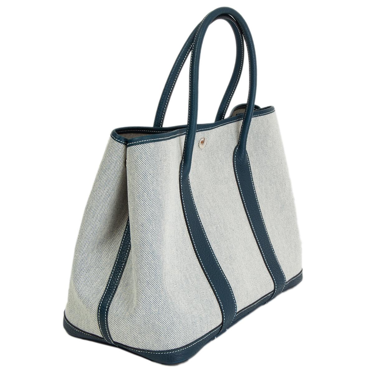 100% authentic Hermès 'Garden Party 36' tote in Ecru (off-white) Toile H canvas with details in Bleu de Prusse Cuir Negonda leather and contrasting white stitching. Unlined. Closes with a snap-button on top. Has been carried and is in excellent