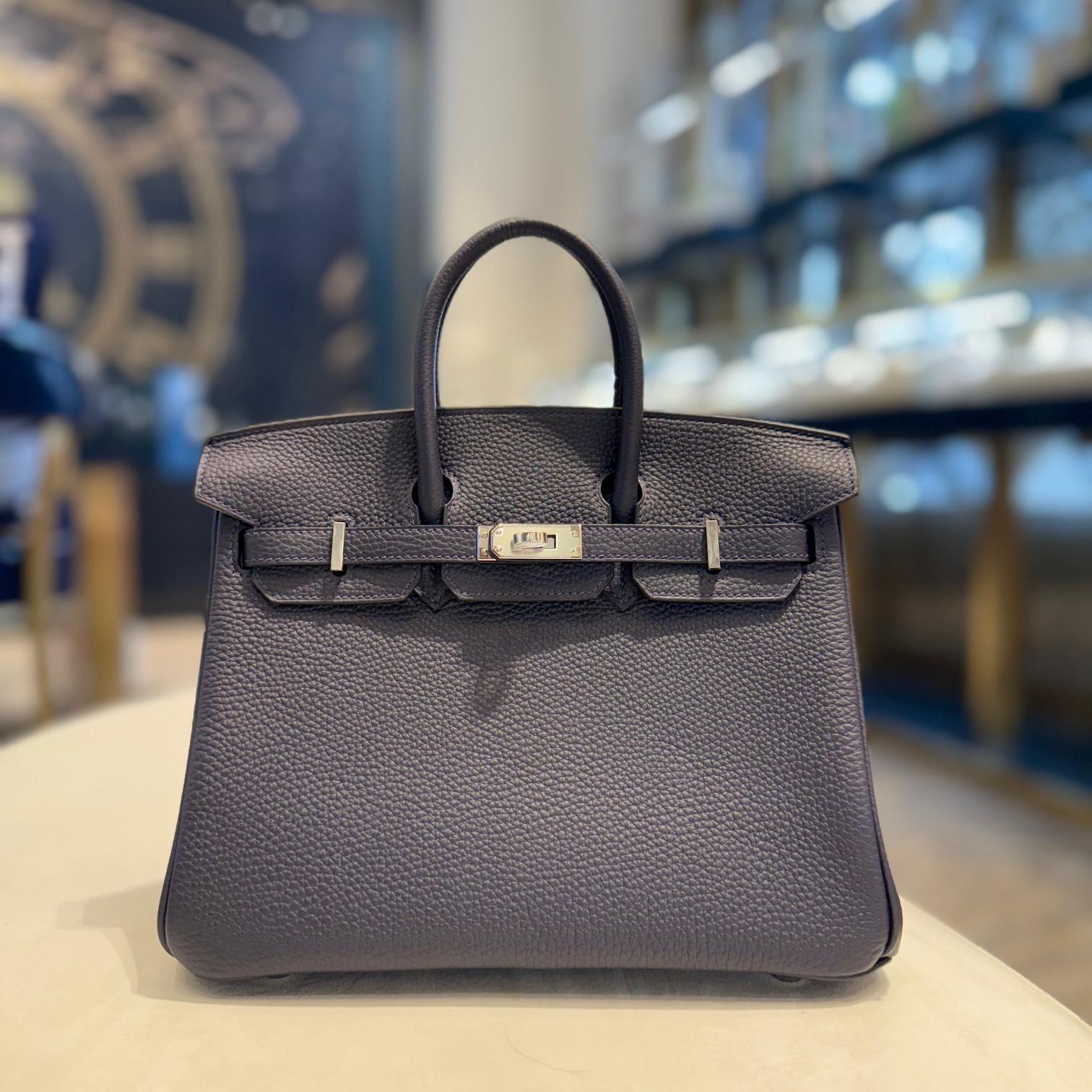 Jewell Aficionado propose le Birkin 25 d'Hermès en cuir Bleu Nuit Togo, une pièce intemporelle d'un bleu marine riche et profond. Confectionné en cuir Togo texturé et durable, il conserve une structure raffinée avec un toucher doux. Fini avec des