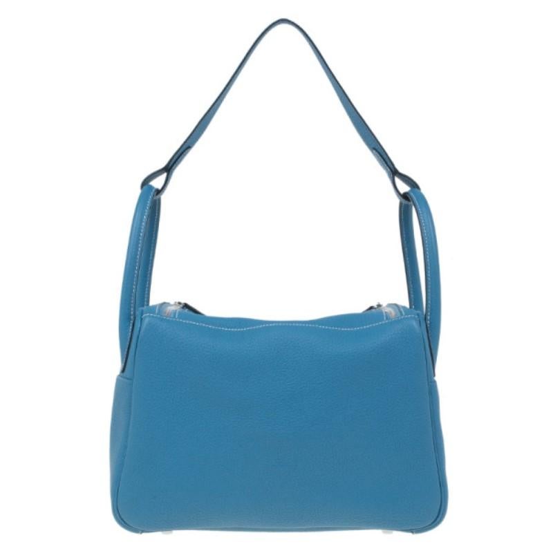This Hermes bag will give you a pop of color. Made from Clemence leather, its turquoise blue color is coupled with white stitching and silver-tone hardware for a look that takes us back to Greek cities. Its twist lock closure opens up to a