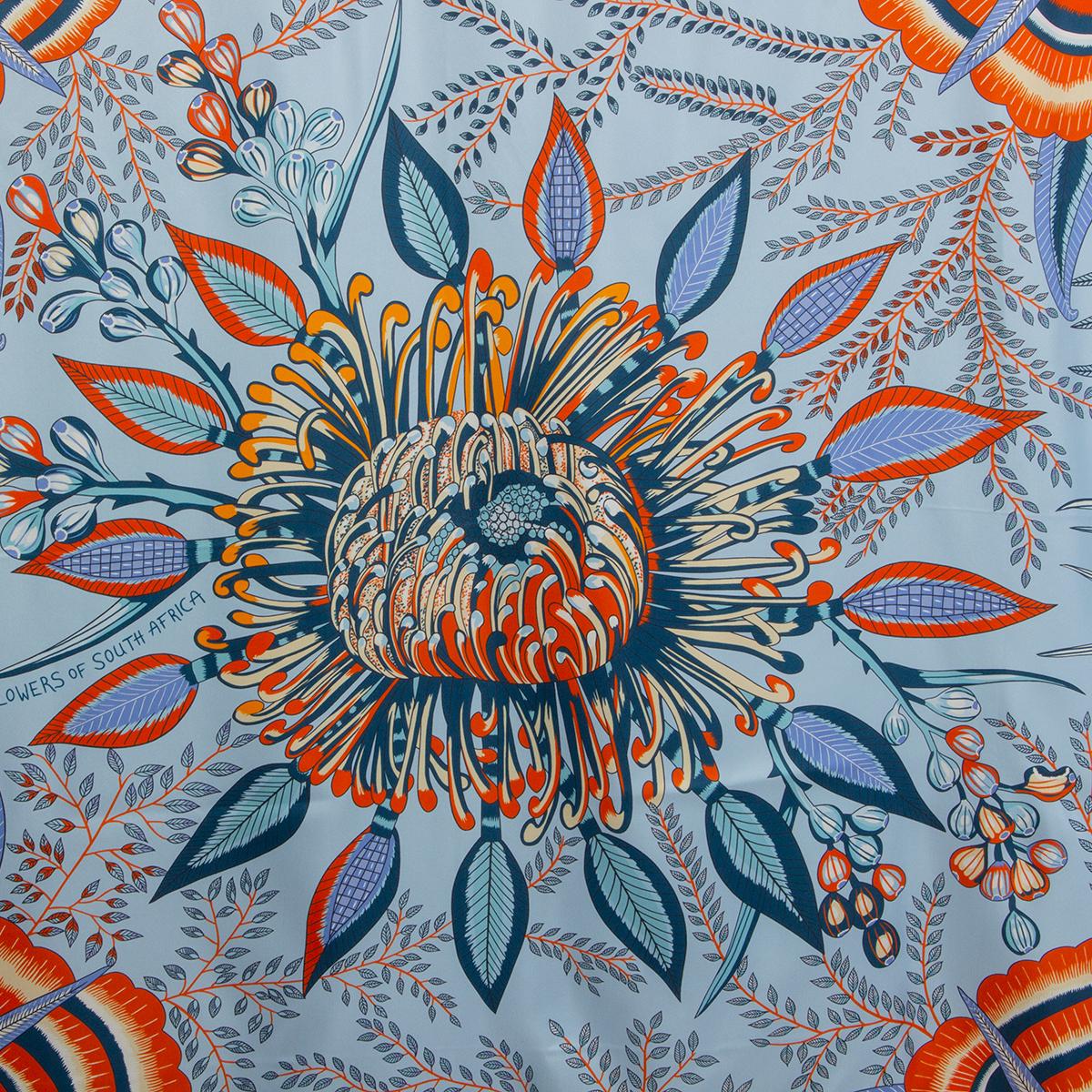 100% authentic Hermès Flowers Of South Africa 140 Geant Scarf in ciel, orange, blue jean light beige and brique silk twill (100%). With hand-rolled edges. Brand new. 

Designed by Ardmore Artists

The strange, South African protea flower has become