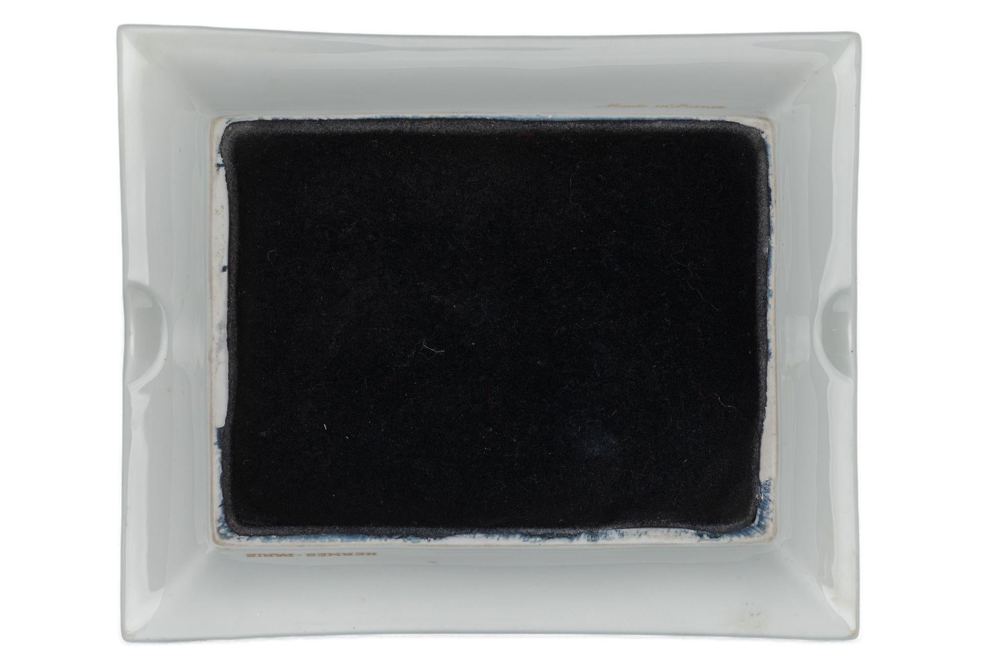 Il posacenere Hermès Paris Knights è realizzato al 100% in porcellana e presenta un motivo a cavalieri, con bordi dorati e fondo in camoscio nero.