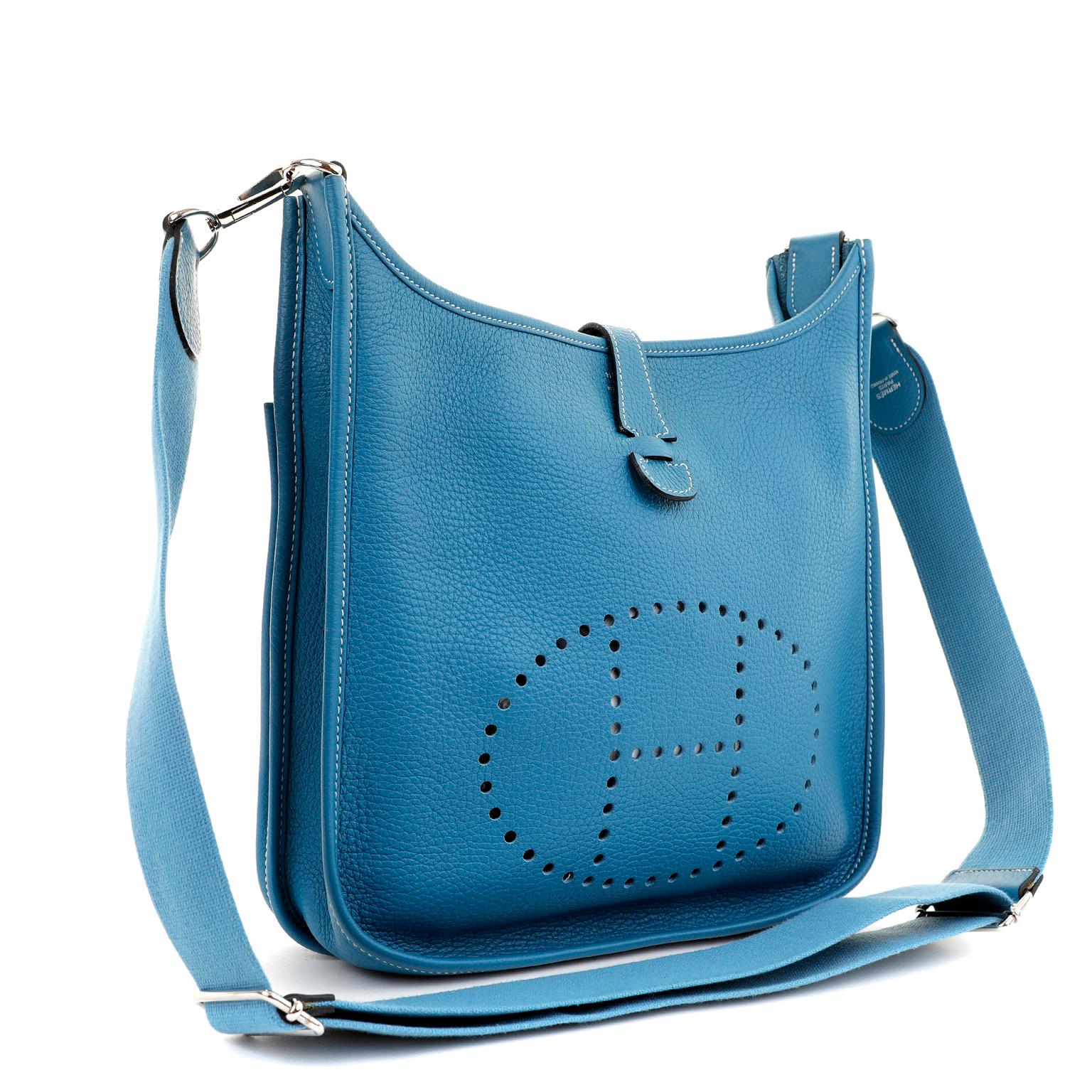 This authentic Hermès Blue Jean Clemence Evelyne GM is in excellent condition. Extremely sought after, the Evelyne is an understated day bag that is stylish and practical. 

The Evelyne silhouette is inspired by an equestrian groom’s tool bag, with
