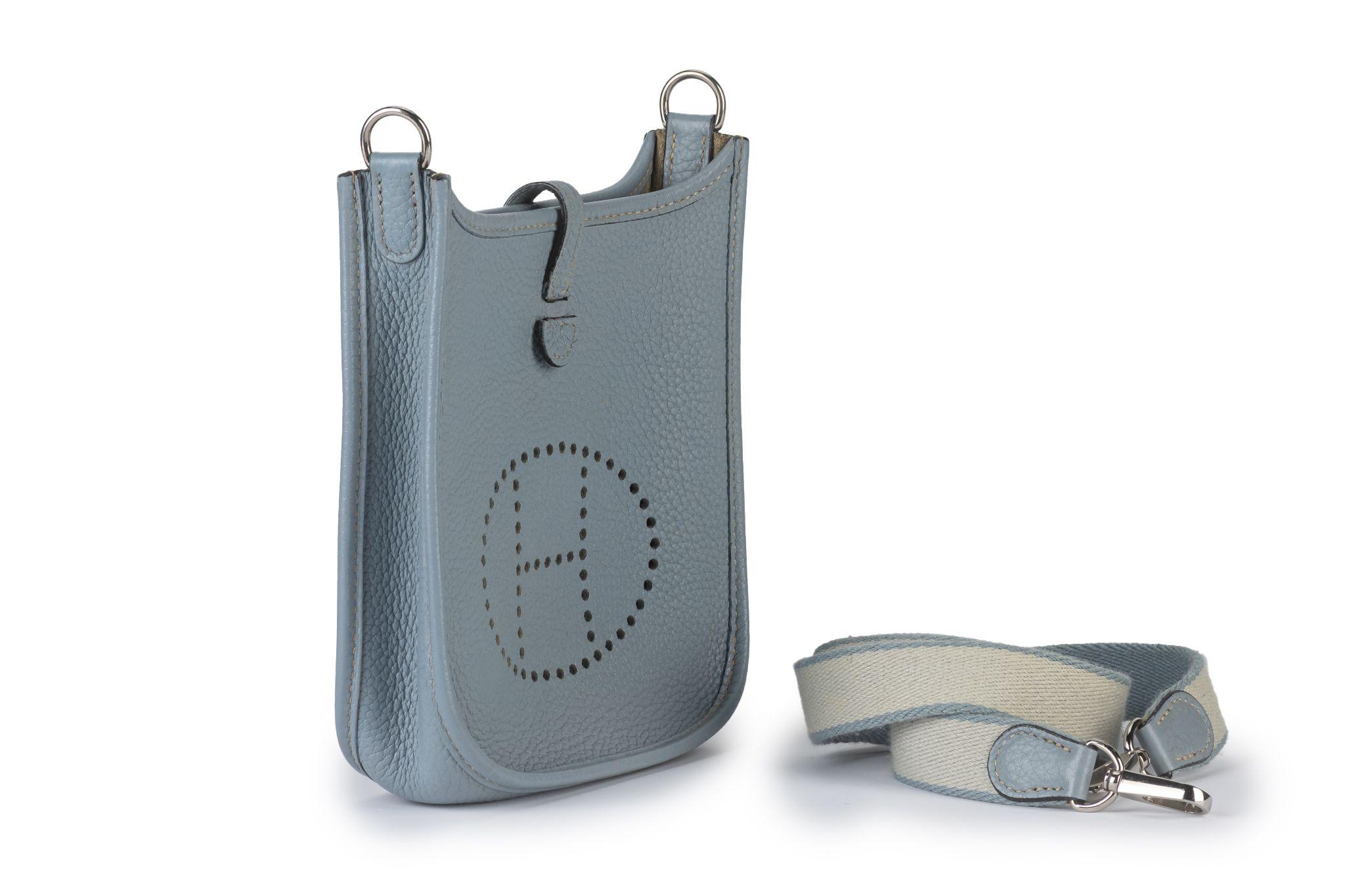 Questa borsa Hermès Mini Evelyne è caratterizzata da pelle Clemence jaune ambre, finiture in palladio, una tracolla piatta staccabile e una parte superiore aperta con chiusura a sacchetto e logo 