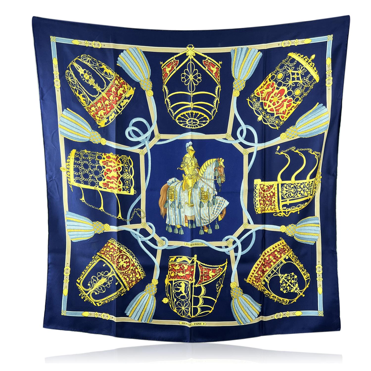 HERMES scarf 'LES MUSEROLLES' by Christiane Vauzelles, originally issued in 1986. The theme of this scarf is a scene depicting a Knight in full armor on a horse, surrounded by nasal masks for horses. Blue background. The 'Hermes Paris' logo with