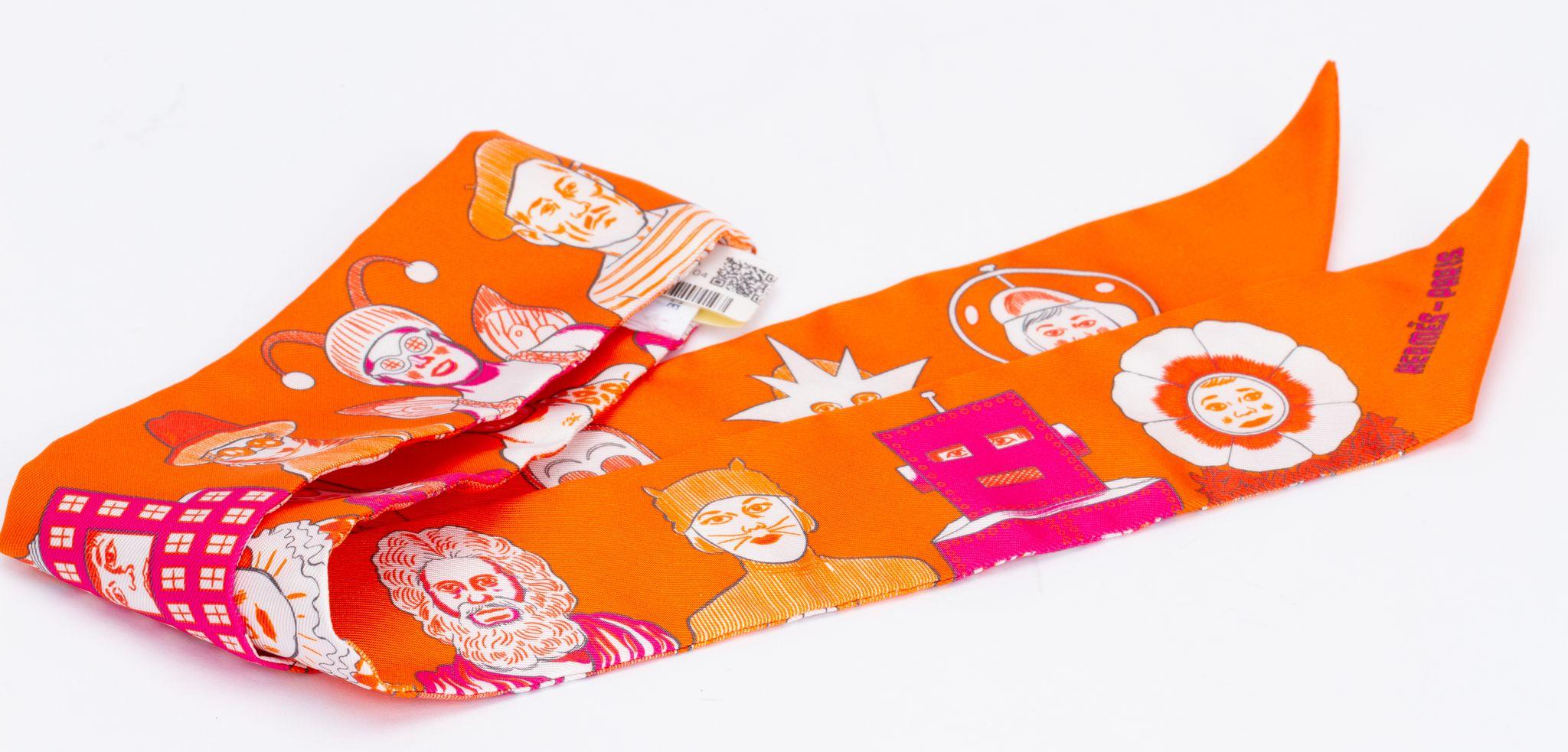 Nuovo Hermès Dresscode Edition twilly. La sciarpa è realizzata in seta e si presenta in un vivace colore arancione. La stampa mostra diversi personaggi, ad esempio la statua della libertà. Il pezzo viene fornito con la scatola e l'astuccio originali.