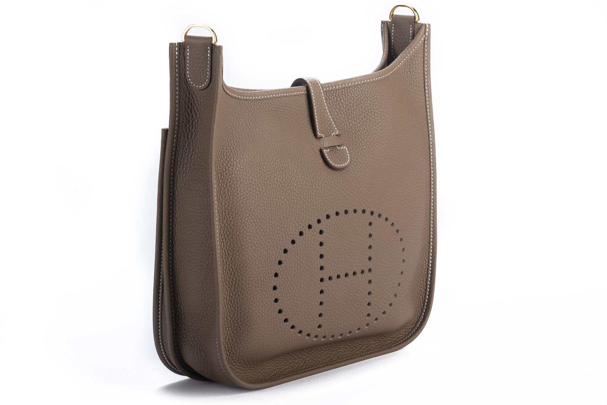 Hermès etoupe clemence leather medium (PM) Evelyne with gold tone hardware. Adjustable shoulder strap, can be worn crossbody. Date stamp Z in a square, 2021. Comes with original duster, shoulder strap, box, and ribbon.
