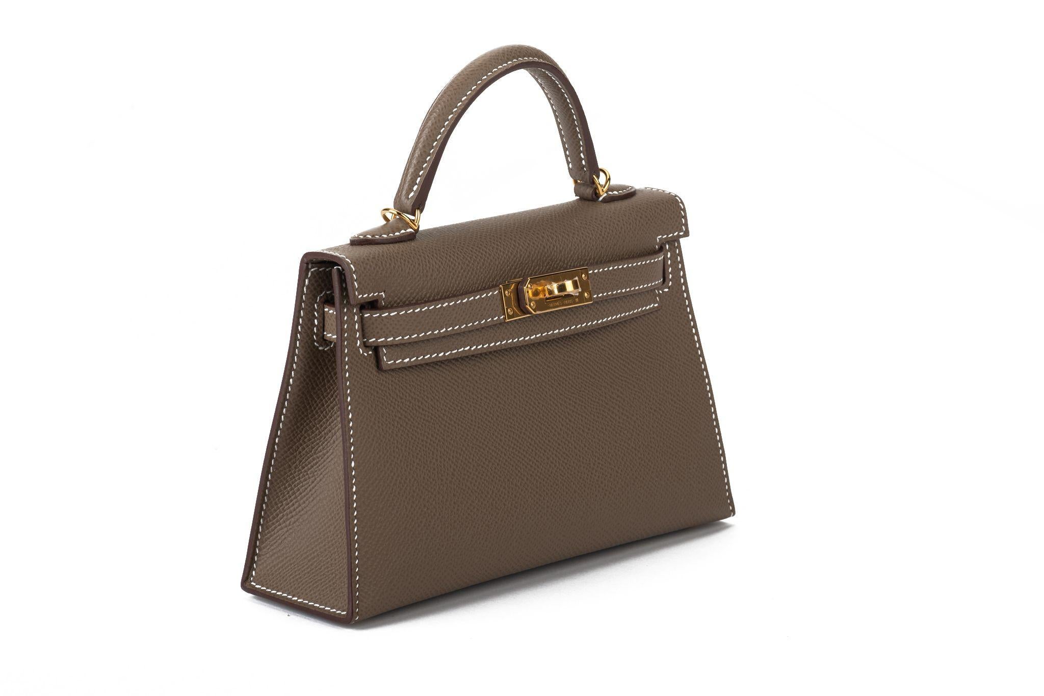 Hermès brand new mini Kelly 20 etoupe epsom leather, white contrast stitching and gold tone hardware. Handle drop 2”. Detachable shoulder strap. Date stamp W for 2024. Comes with booklet, original dust cover and box. Blacked our receipt.