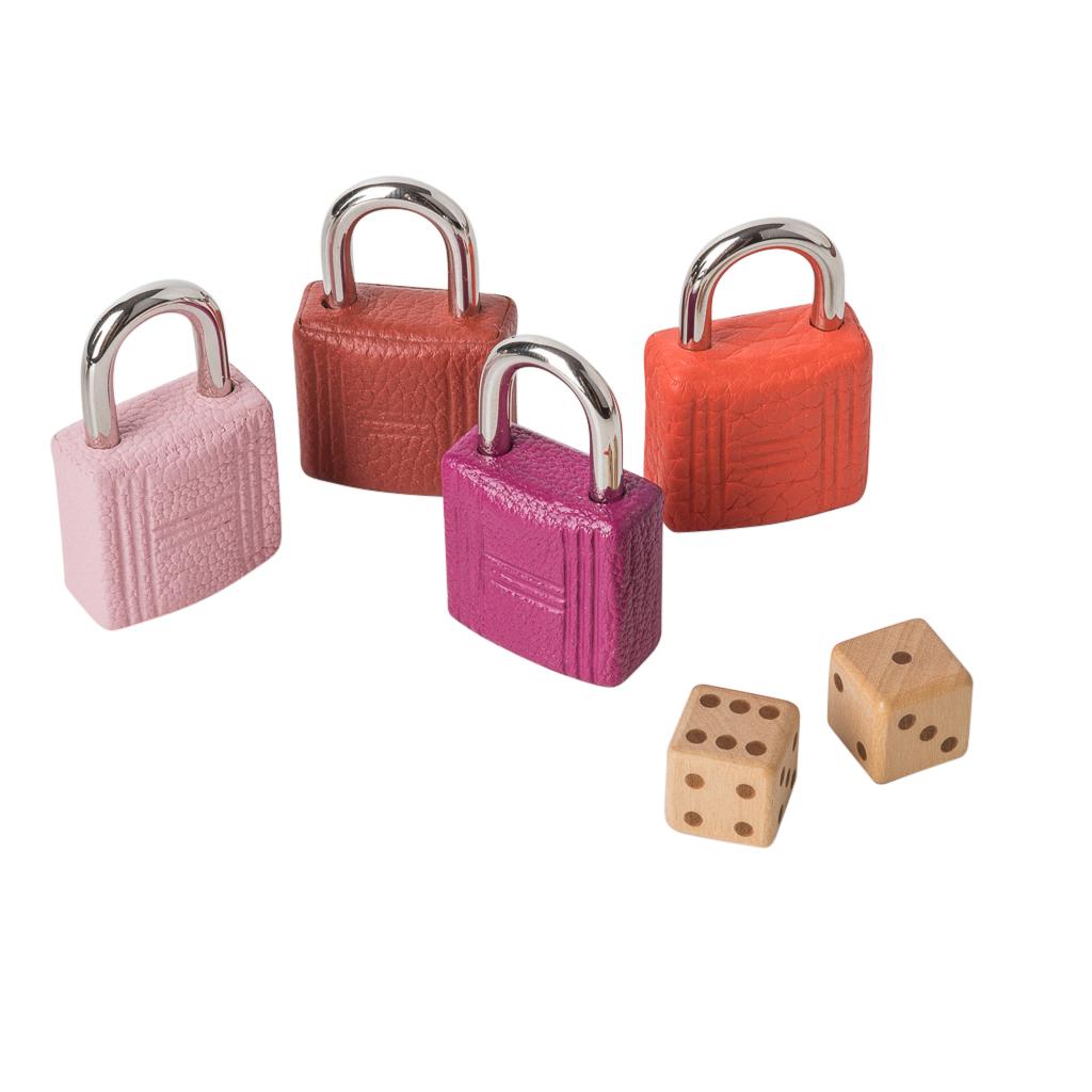 Guaranteed authentic limited edition Hermes Board game with a whimsical take on Snakes and Ladders. 
Multi coloured leather covered padlocks with palladium hardware. 
Marquetry dice.  
Leather Rouge H playing board with coveted 5P pink