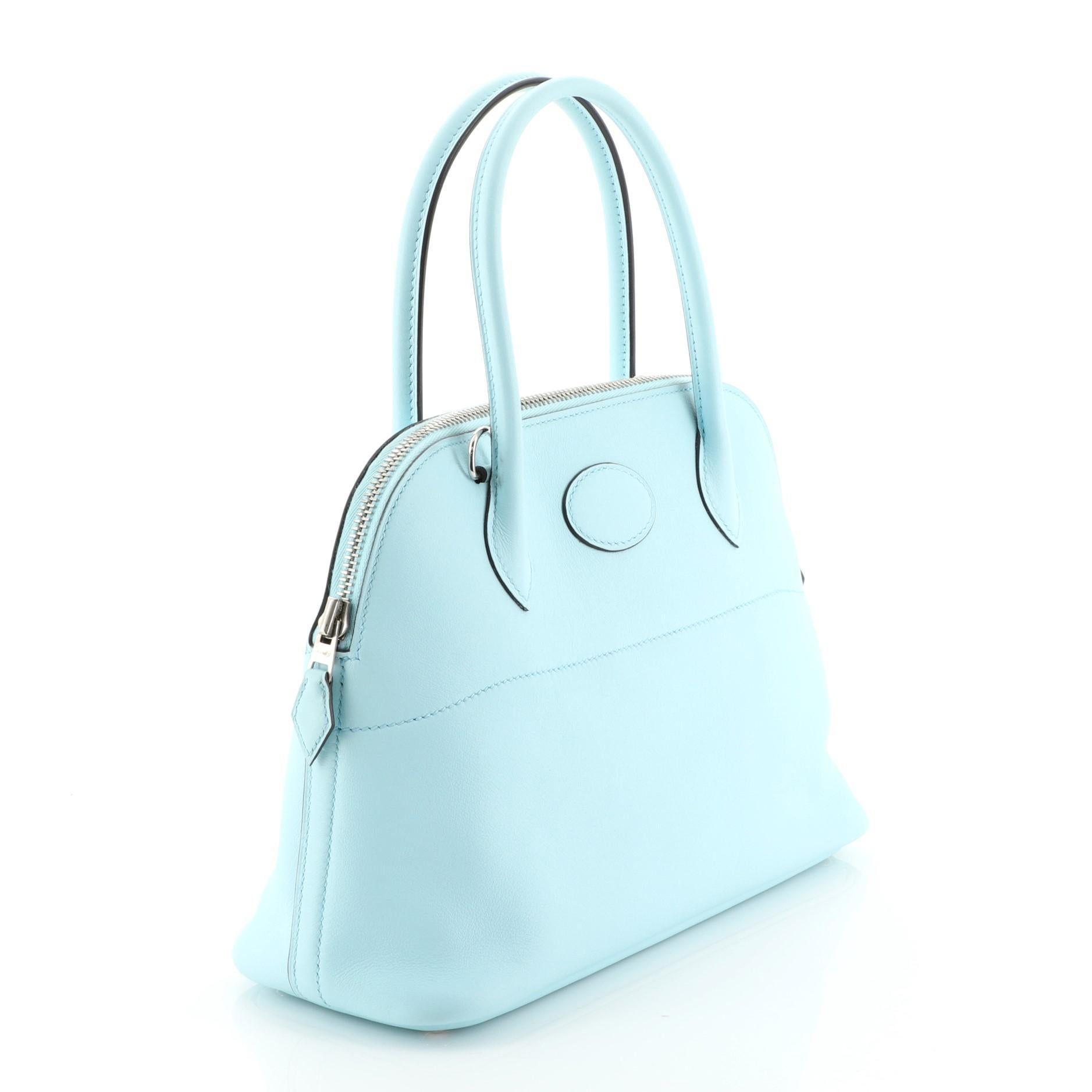 This Hermes Bolide Handbag Swift 27, crafted from Bleu Zephyr blue Swift leather, features dual rolled leather handles, protective base studs, and palladium hardware. Its zip closure opens to a Bleu Zephyr blue Swift leather interior. Date stamp