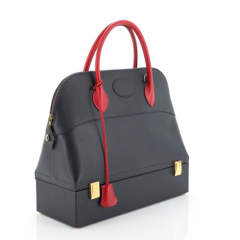 This Hermes Bolide Macpherson Handbag Courchevel 34, crafted from Bleu Marine blue and Rouge Vif red Courchevel leather, features dual rolled leather handles, protective base studs, base compartment with flip-lock closure, and gold hardware. Its zip