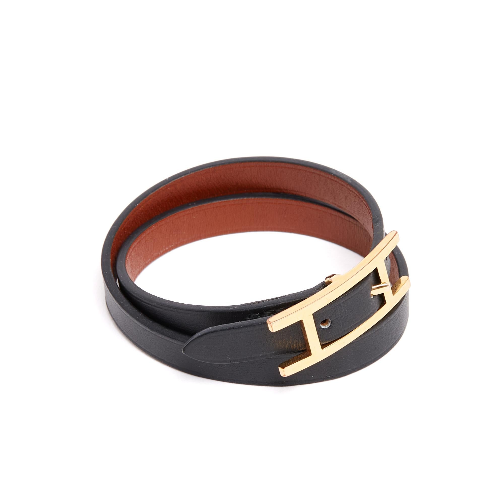 Pulsera Hermès Behapi de doble vuelta de cuero negro liso, reversible a camel o dorado, y metal chapado en oro (latón). Talla 1, o XS, para una circunferencia de muñeca de 14,5 cm. La pulsera debe de haberse usado muy poco y está en muy buen estado.