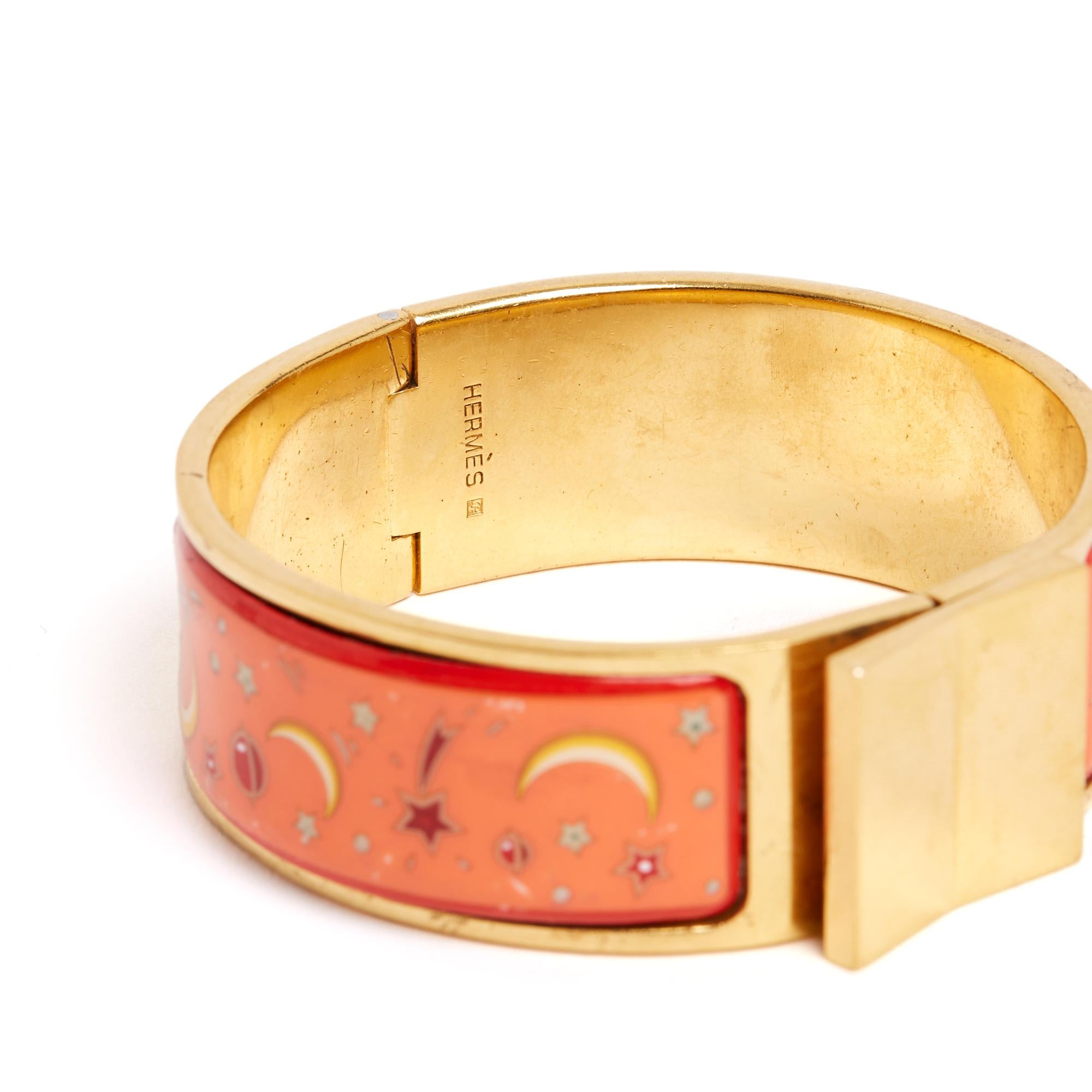 Vintage Hermès Clic Clac bracelet (circa 1990) Large version in gold-plated and orange metal with red edges and a star and moon motif, swivel clasp. GM size for a wrist circumference of 17 cm, bracelet width 2 cm. The enamel has a few tiny chips and