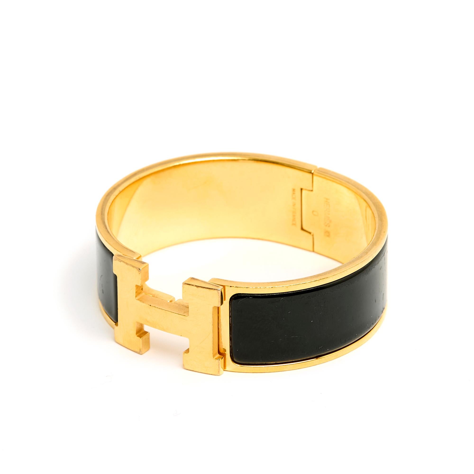 Pulsera Hermès Clic Clac H, versión grande, de metal dorado y esmalte negro con cierre giratorio. Talla GM para una circunferencia de muñeca de 17 cm, ancho de pulsera de 2 cm. La pulsera está marcada, principalmente arañada (pero no patinada) en el