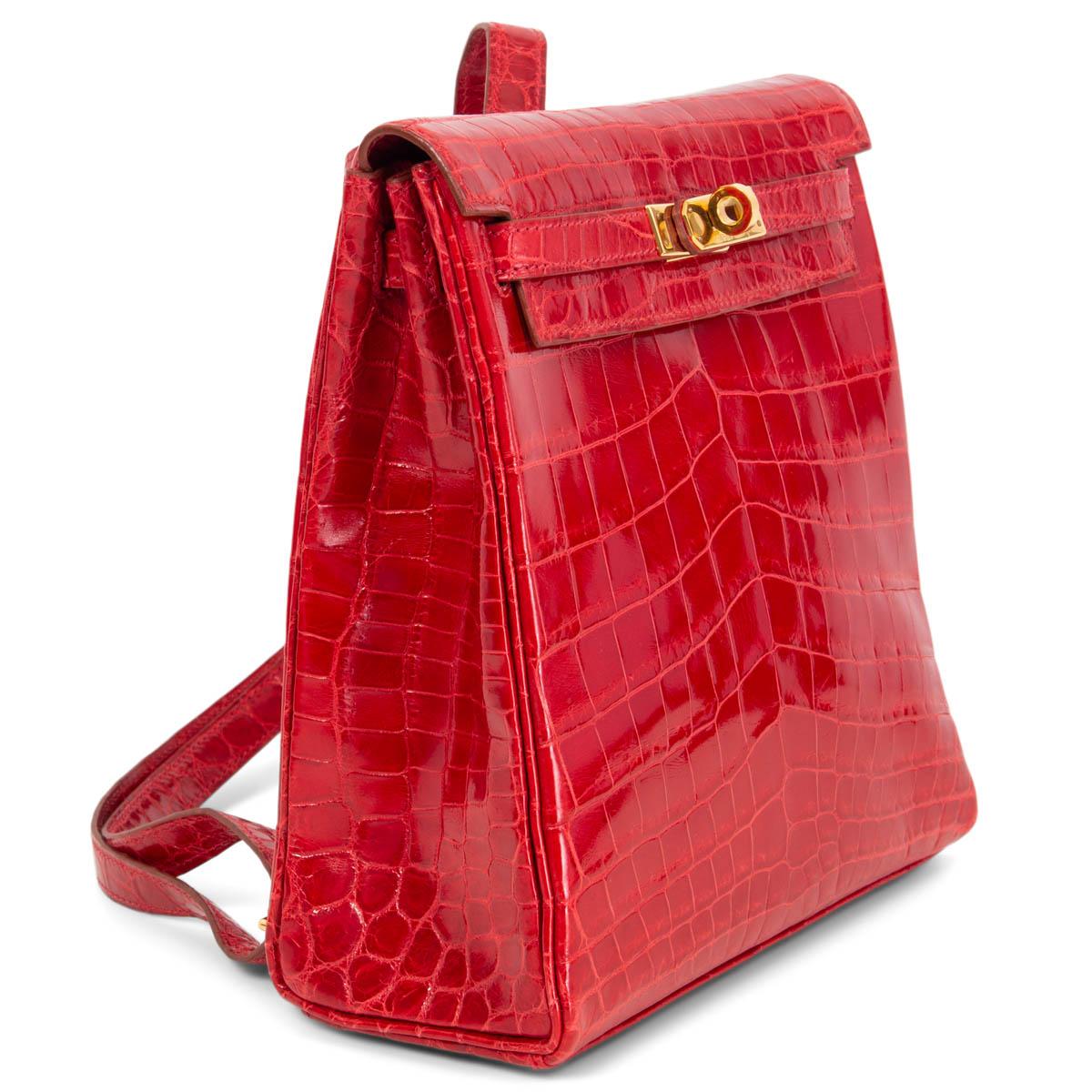 100% authentic Hermès Kelly A Dos backpack in Braise (bright red) shiny porous crocodile featuring gold-tone hardware and classic Kelly belt-style closure. Has two adjustable backpack straps and is lined in red Chevre leather with one slip pocket