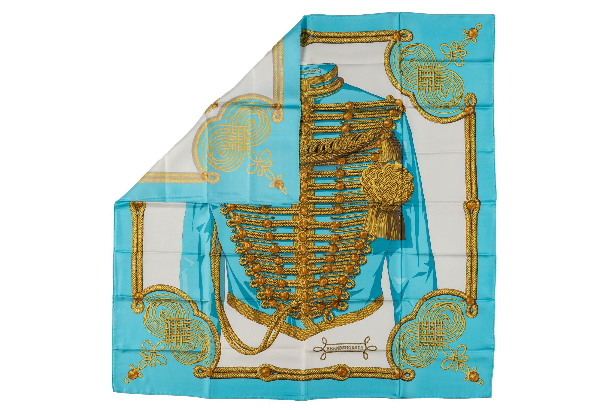 The Hermès Brandenburgs scarf was designed by Cathy Latham and published in 1972. The scarf is made from 100% silk with hand-rolled edges with a beautiful blue border. Comes with no label and no box.
