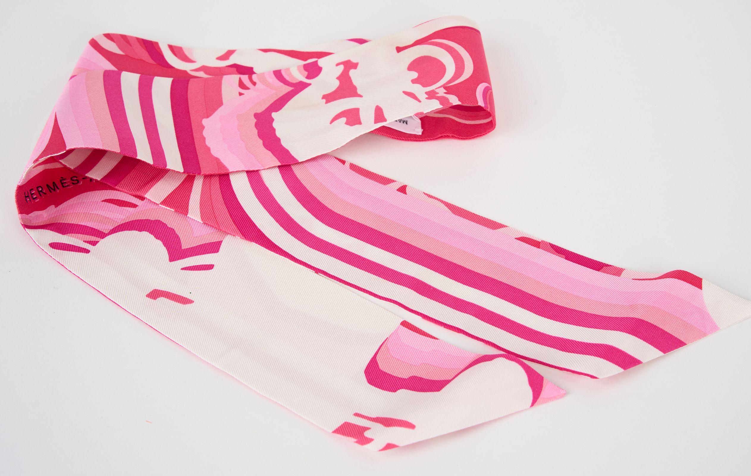 Esta Sombra Hermès Bridges De Gala Twilly es de color Rosa, Blanco y Fucsia. De seda 100%. Se puede llevar de diferentes maneras con un medor deslizante en herrajes de tono dorado. Viene con caja original. A estrenar.