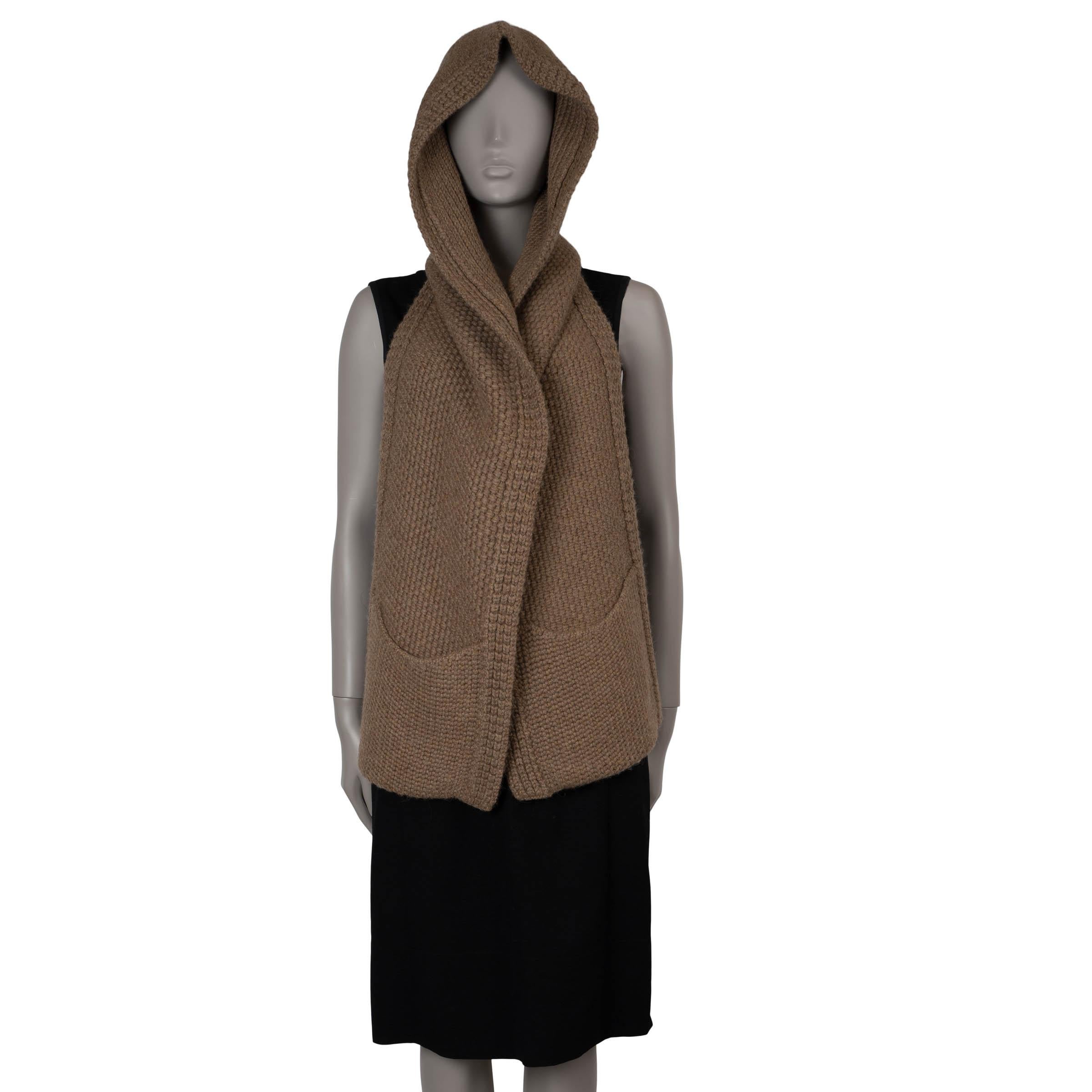 Questa sciarpa a maglia grossa di Hermès, autentica al 100%, è realizzata in alpaca marrone chiaro (100%) per garantire calore e morbidezza. Presenta un pratico cappuccio, due tasche applicate e finiture a costine, che combinano un comfort