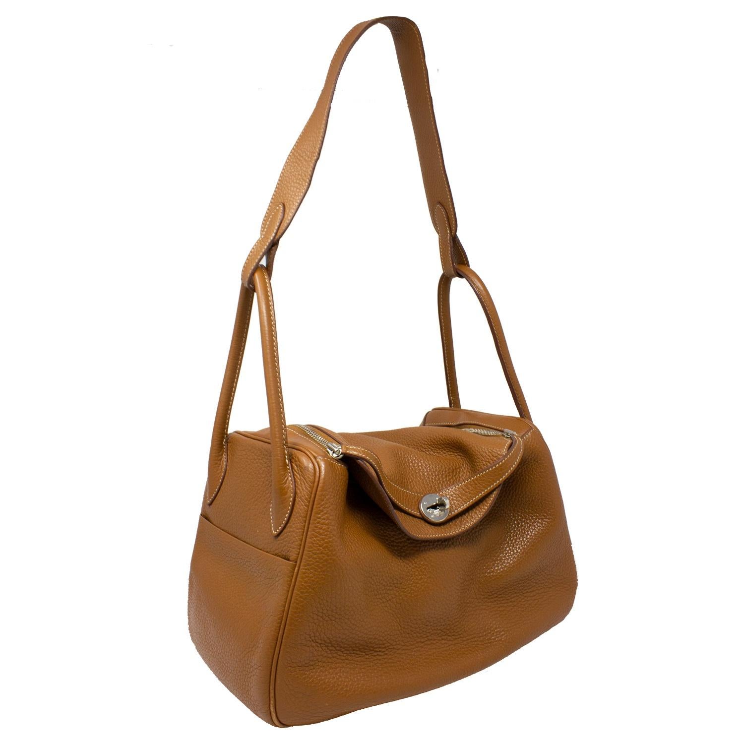 Gorgeous and elegant Lindy crafted in brown Clemence leather with silver-tone hardware, a single shoulder strap and top handles, double side exterior pockets, and protective feet to the base. The zip closure at top opens up to a tonal brown spacious