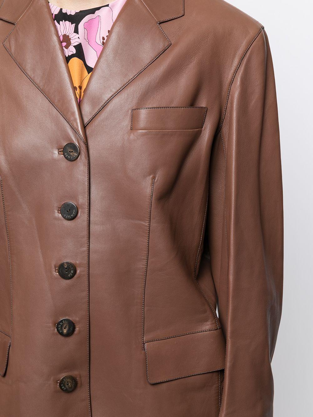 Expertly cut and crafted from smooth brown lambskin and a delightful silk lining, this vintage, long sleeved blazer features a classic cut and a four button closure. The strong silhouette of this blazer makes it a perfect statement piece any time of