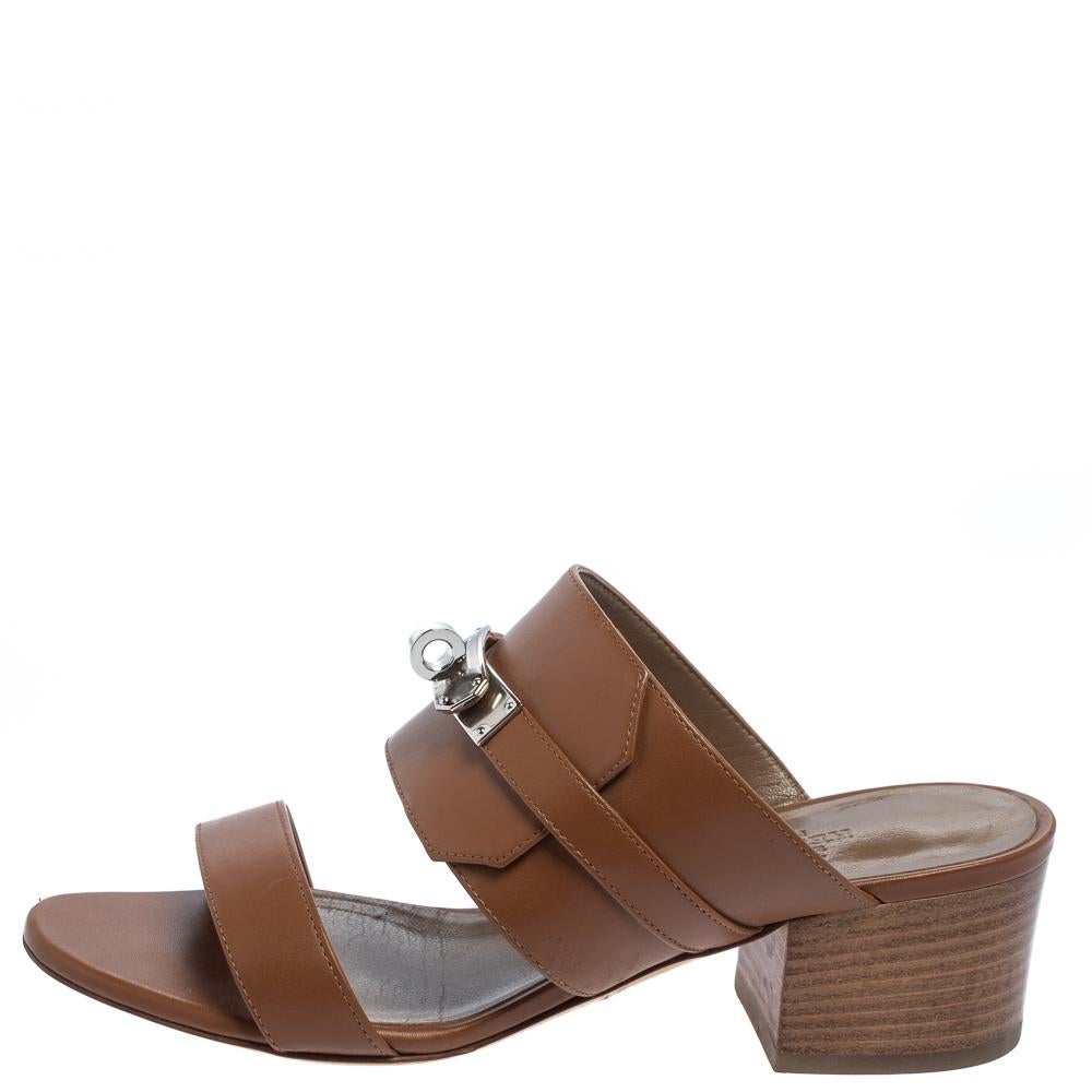These brown leather slides from Hermès are a pair of simple and casual shoes. These slides have a slender strap at the toes and a broader one at the vamps accented with the signature Kelly lock in silver-tone. It is finished with open toes and 6 cm